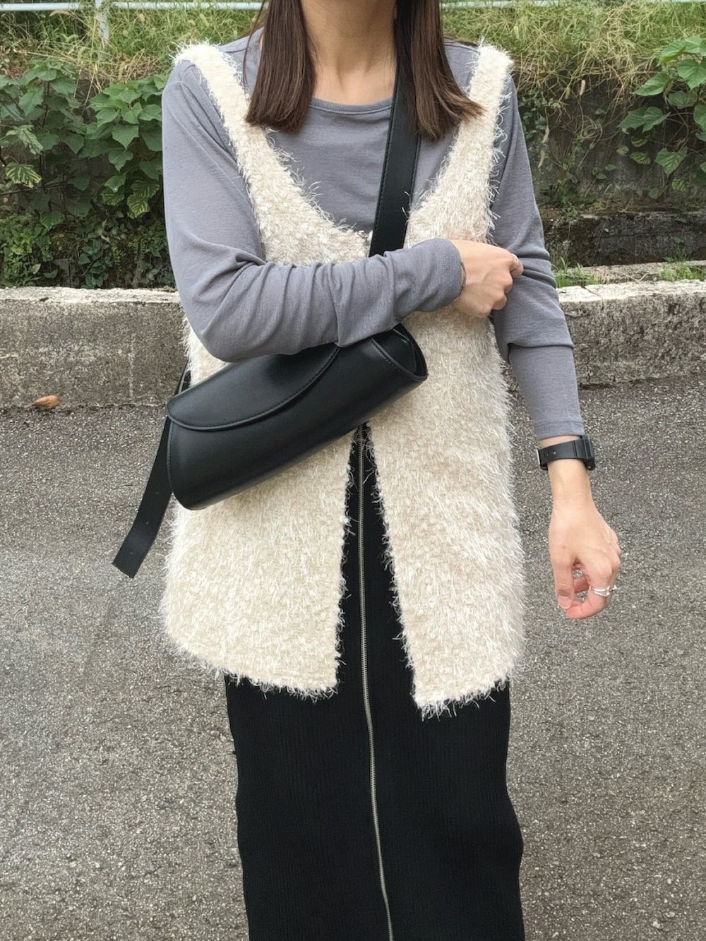 グレー系のTシャツ/カットソー、ホワイト系のベスト、ブラック系のスカートを着用したレディースの秋コーディネートの5枚目の写真