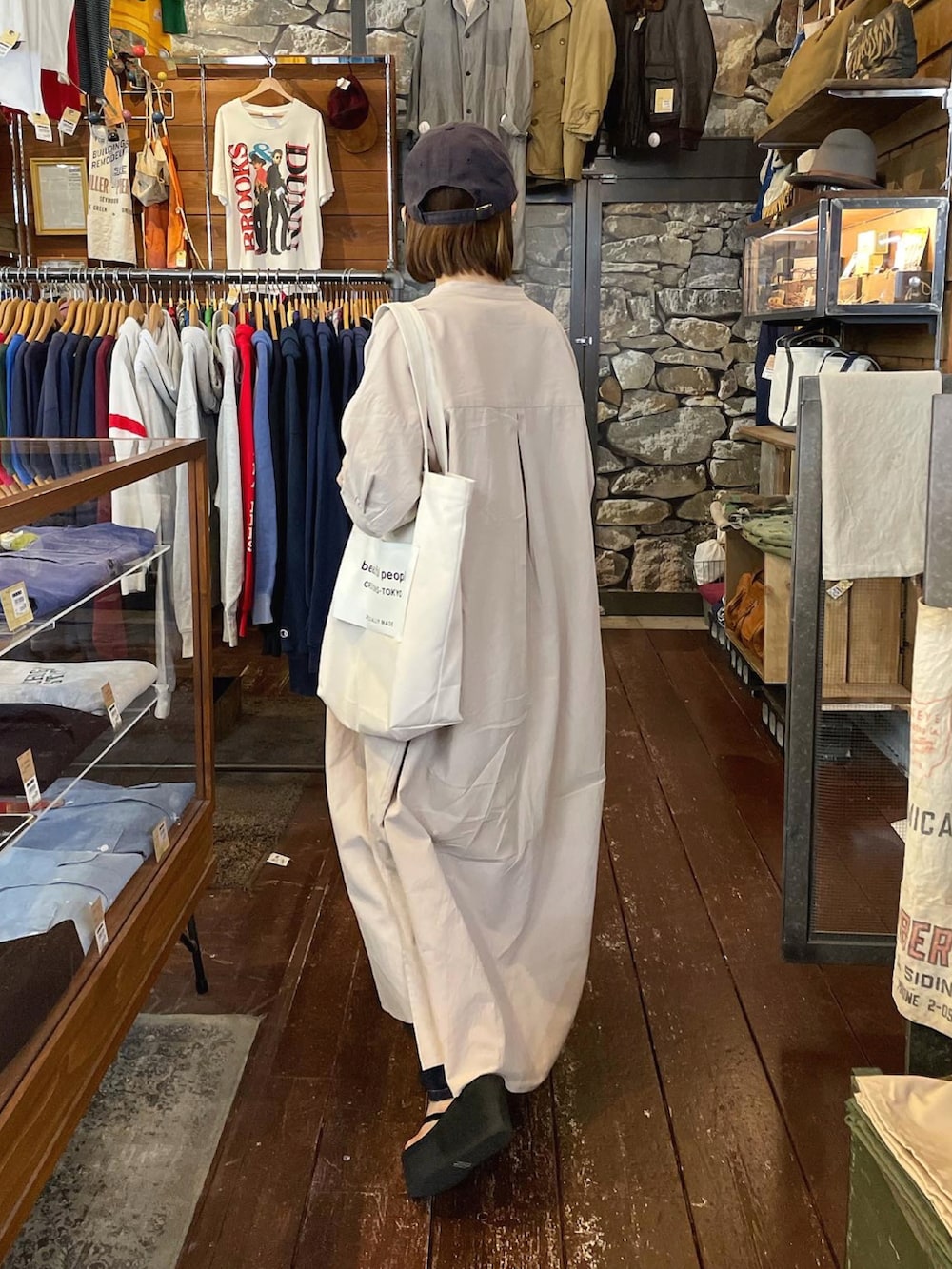 グレー系のシャツワンピース、ホワイト系のトートバッグ、ベージュ系のタンクトップを着用したレディースの夏コーディネートの2枚目の写真