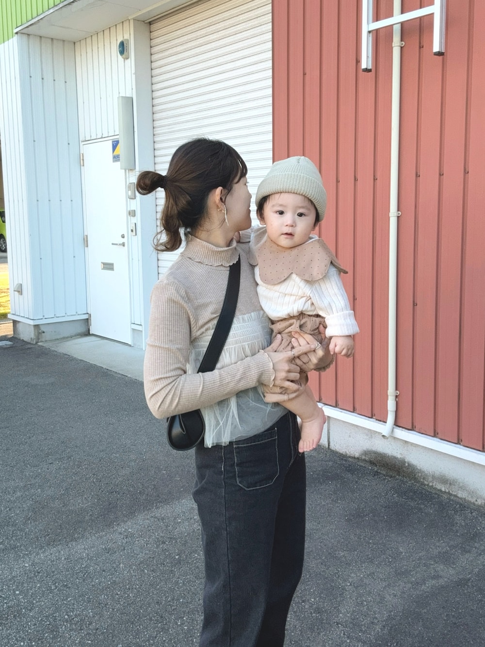 ベージュ系のTシャツ/カットソー、ブラック系のデニムパンツ、ブラック系のショルダーバッグを着用したレディースの秋コーディネートの2枚目の写真
