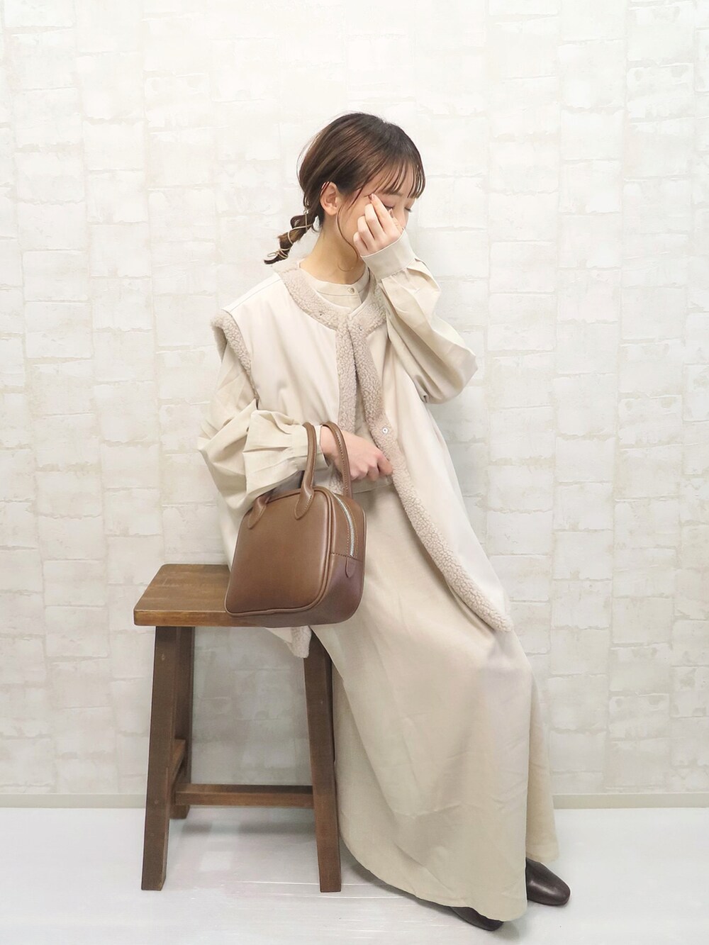 ベージュ系のワンピース、ホワイト系のその他アウター、ブラウン系のショルダーバッグを着用したレディースの冬コーディネートの2枚目の写真