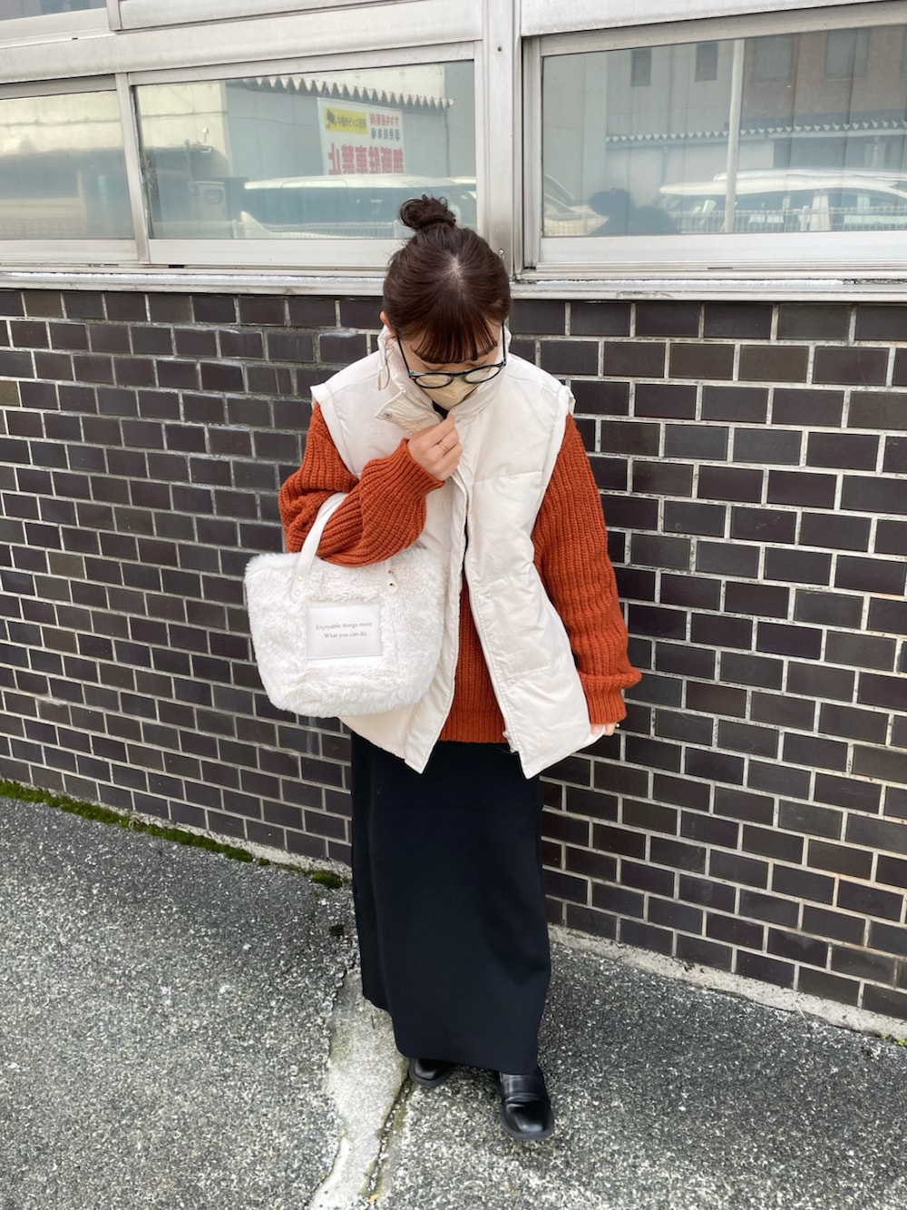 イエロー系のニット/セーター、ホワイト系のダウンベスト、ブラック系のスカートを着用したレディースの秋コーディネートの3枚目の写真