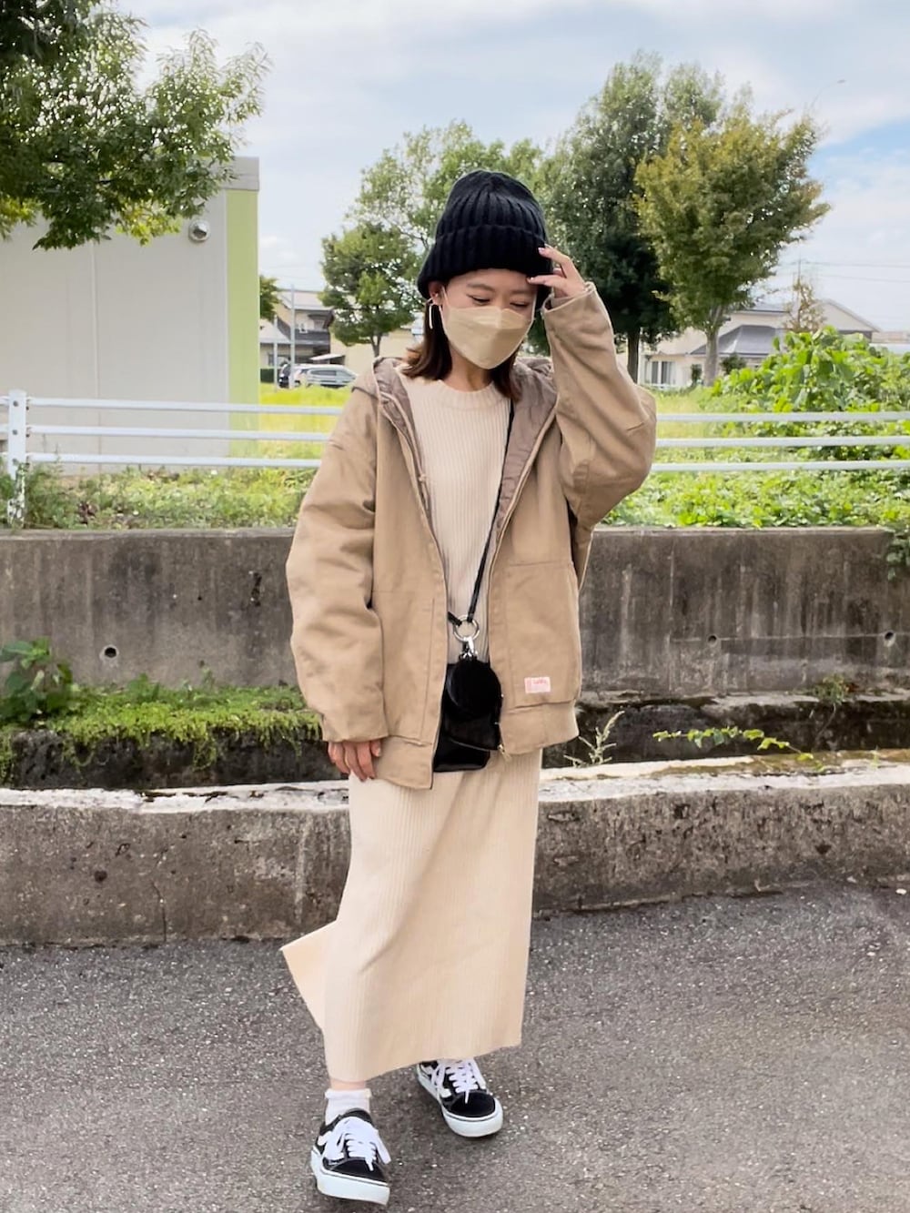 ベージュ系のブルゾン、ホワイト系のワンピース、ブラック系のショルダーバッグを着用したレディースの秋コーディネートの2枚目の写真