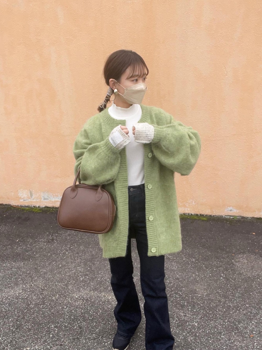 グリーン系のカーディガン/ボレロ、ホワイト系のニット/セーター、ブラウン系のショルダーバッグを着用したレディースの冬コーディネートの2枚目の写真