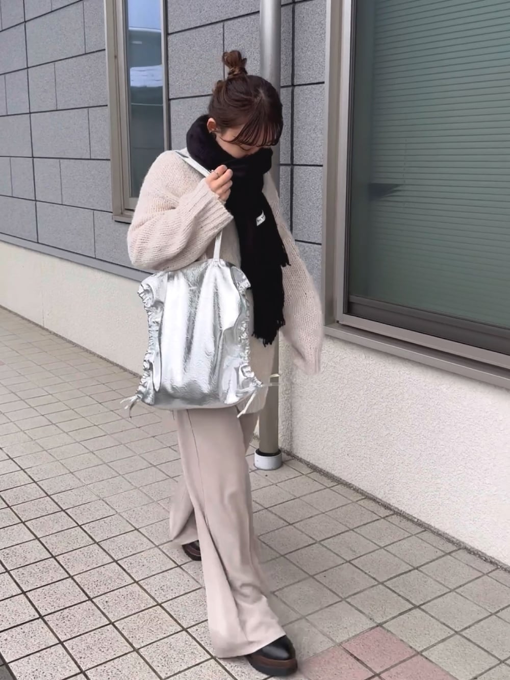 シルバー系のトートバッグ、ホワイト系のニット/セーター、ホワイト系のパンツを着用したレディースの冬コーディネートの5枚目の写真