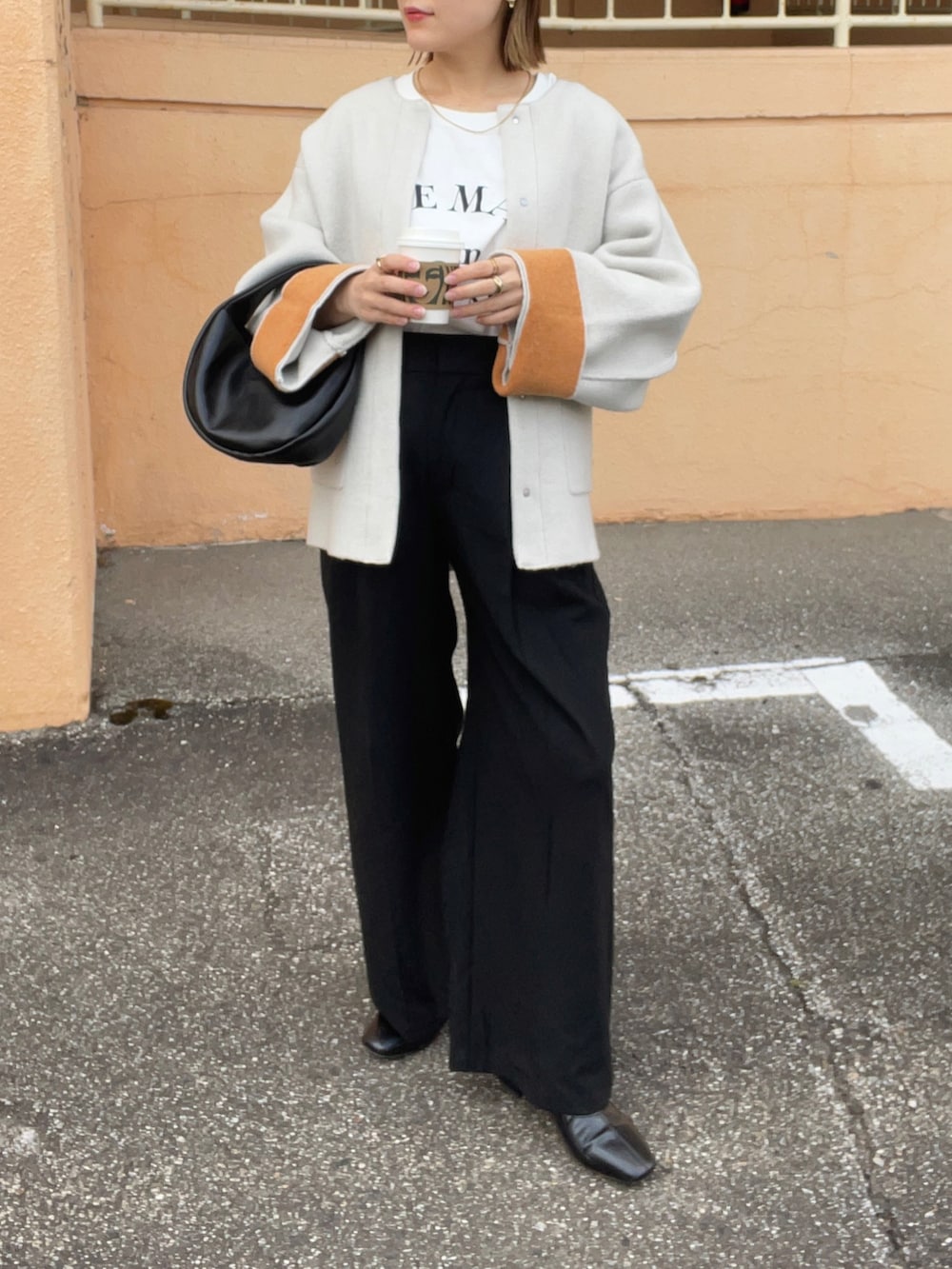 ベージュ系のノーカラーコート、ホワイト系のTシャツ/カットソー、ブラック系のパンツを着用したレディースの秋コーディネートの4枚目の写真