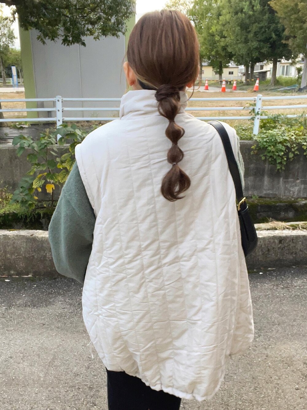 グリーン系のニット/セーター、ホワイト系のジャケット/アウター、ブラック系のバッグを着用したレディースの秋コーディネートの4枚目の写真