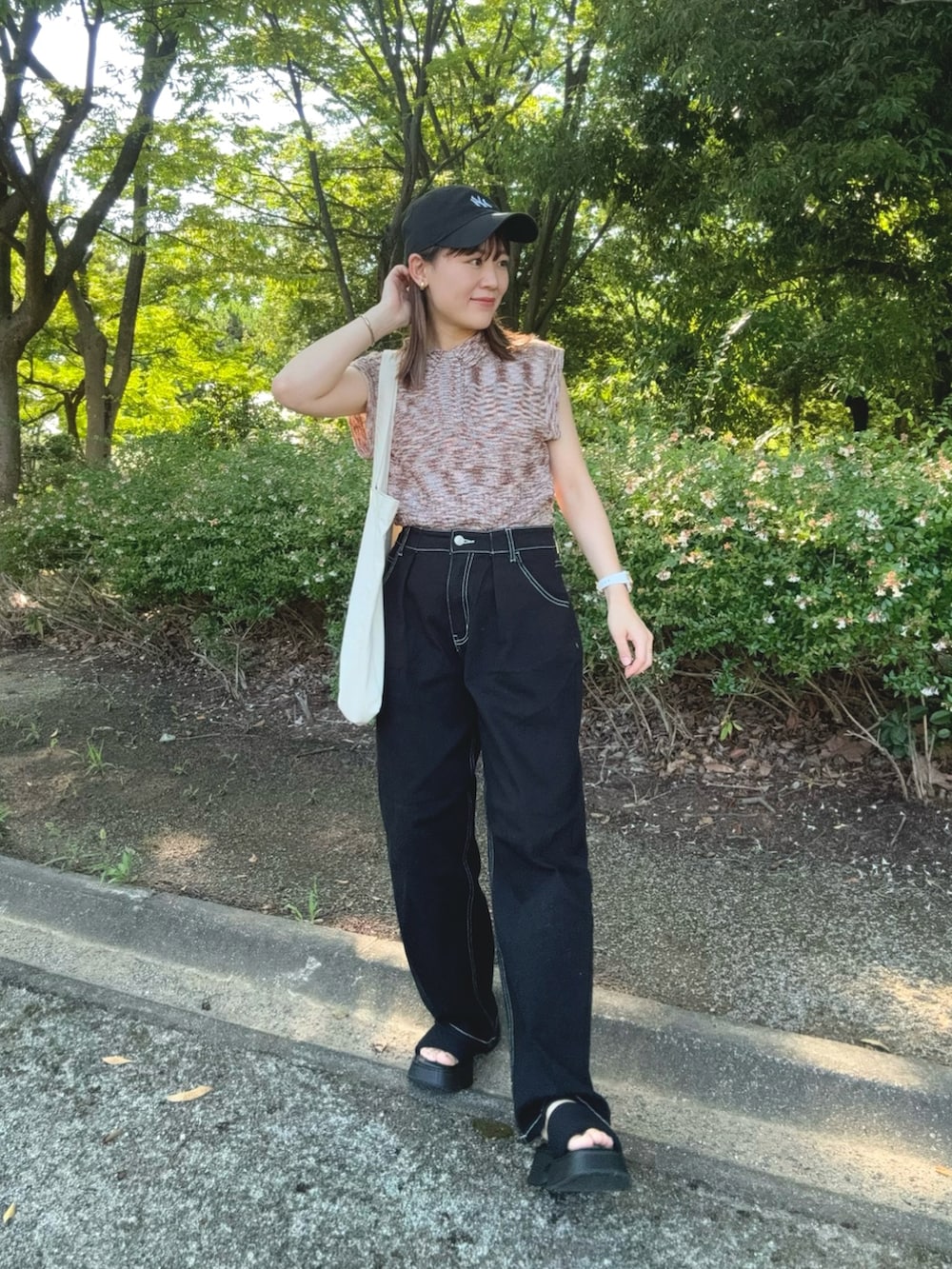 ピンク系のニット/セーター、ブラック系のデニムパンツ、ブラック系のサンダルを着用したレディースの夏コーディネートの3枚目の写真