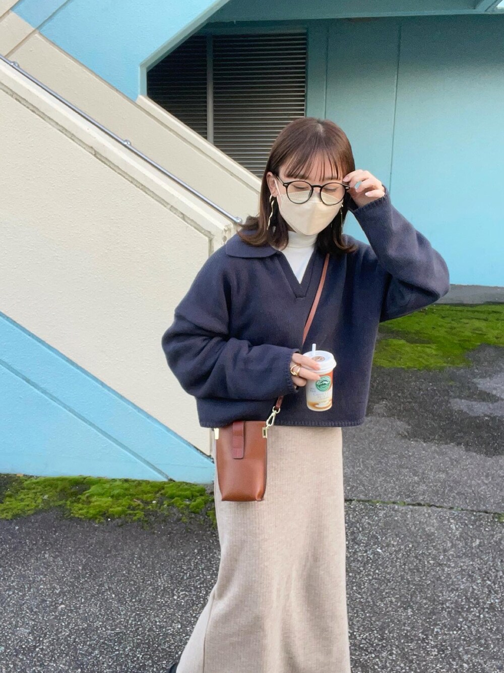 グレー系のニット/セーター、ホワイト系のTシャツ/カットソー、ベージュ系のスカートを着用したレディースの秋コーディネートの2枚目の写真