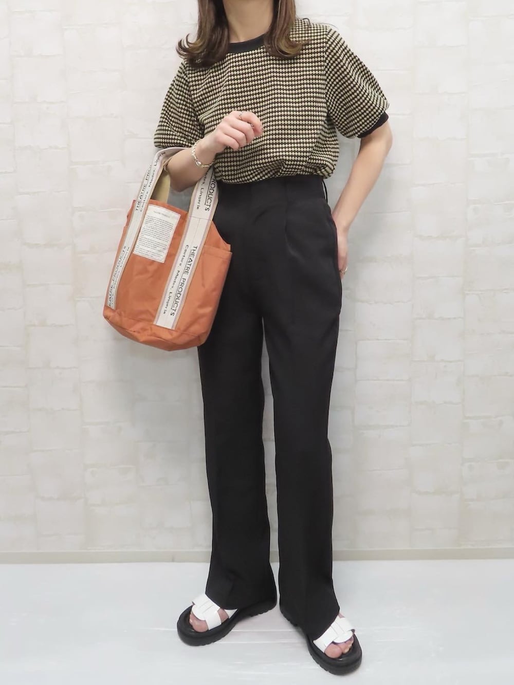 ブラック系のTシャツ/カットソー、オレンジ系のトートバッグ、ブラック系のスラックスを着用したレディースの春コーディネートの3枚目の写真