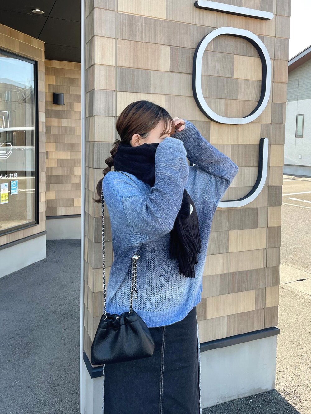 ブルー系のニット/セーター、ブラック系のショルダーバッグ、ホワイト系のスニーカーを着用したレディースの冬コーディネートの5枚目の写真