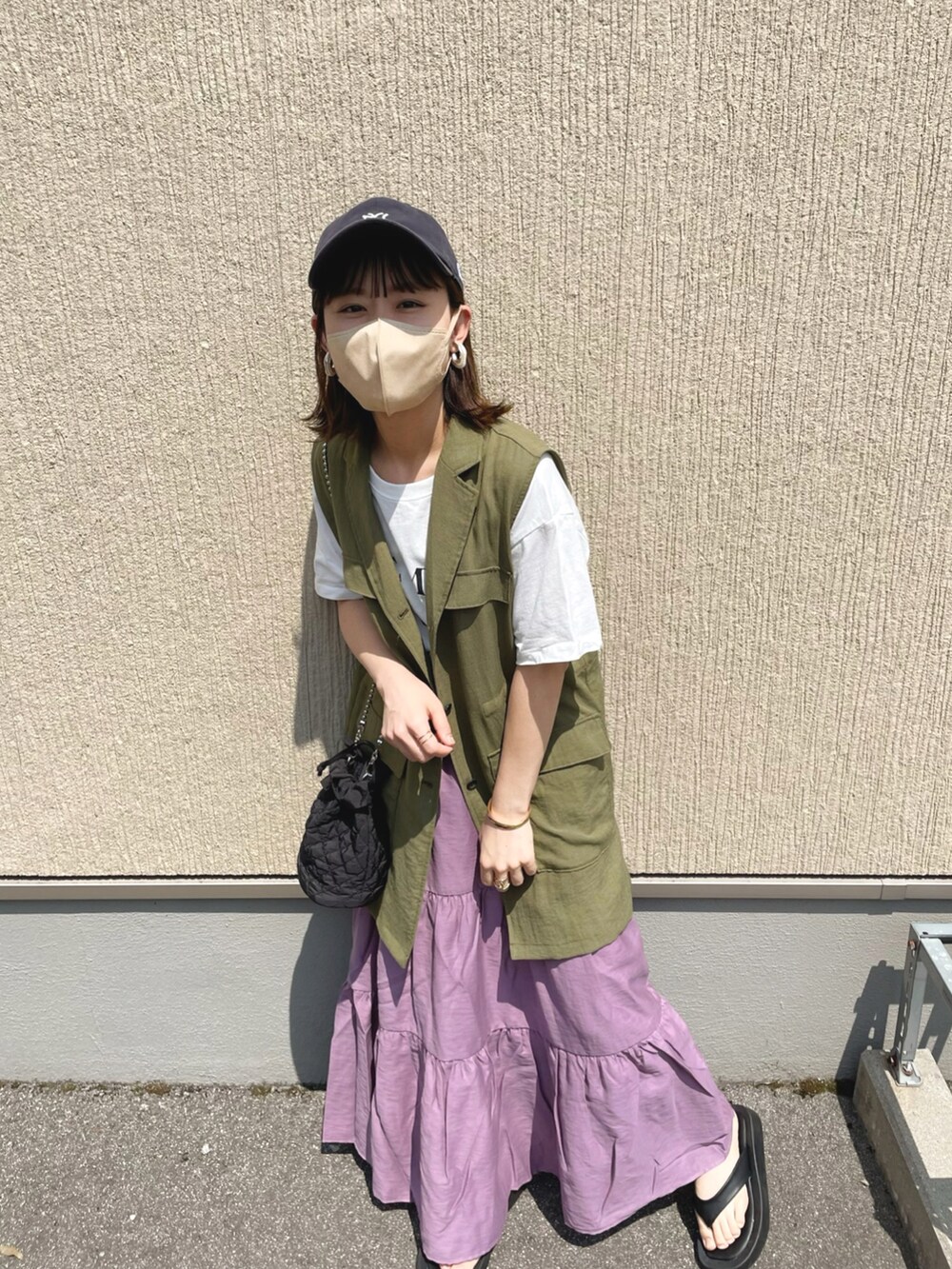 パープル系のスカート、ホワイト系のTシャツ/カットソー、ブラック系のサンダルを着用したレディースの夏コーディネートの3枚目の写真