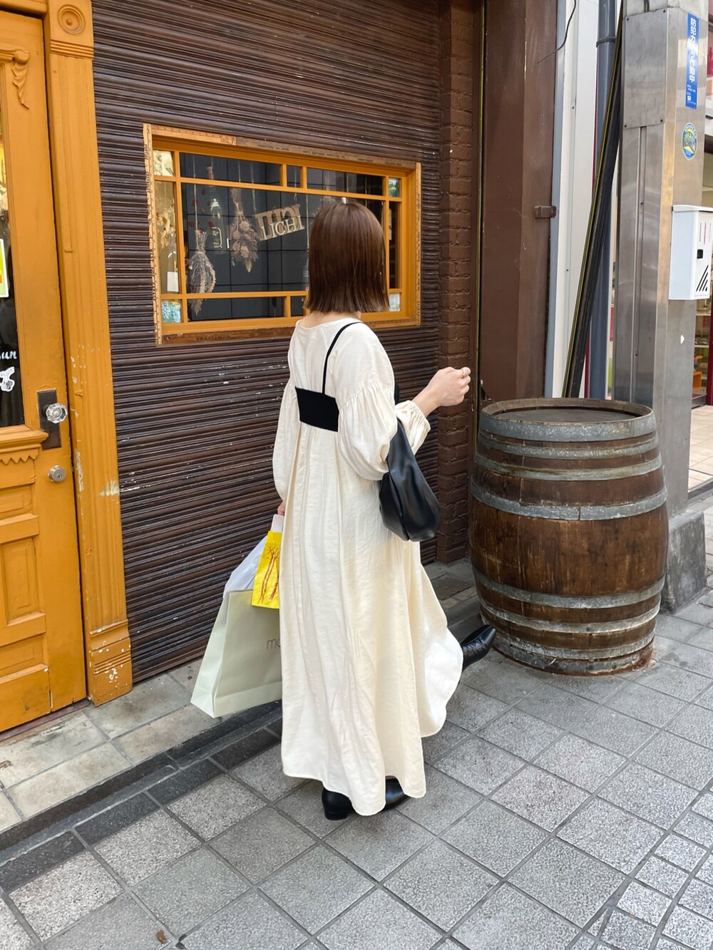 ホワイト系のワンピース、ブラック系のハンドバッグ、ブラック系のブーツを着用したレディースの秋コーディネートの5枚目の写真