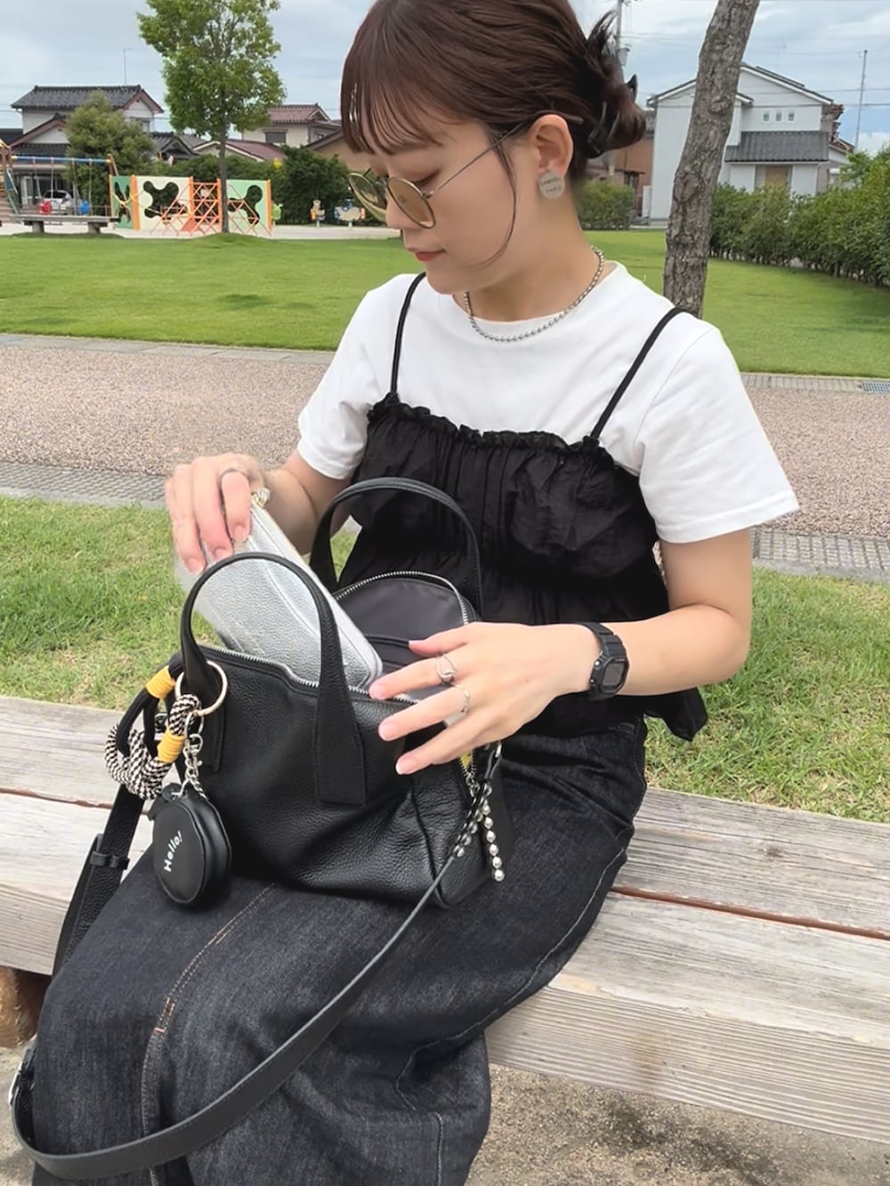 ブラック系のサンダル、ブラック系のボストンバッグ、ブラック系のデニムスカートを着用したレディースの夏コーディネートの3枚目の写真