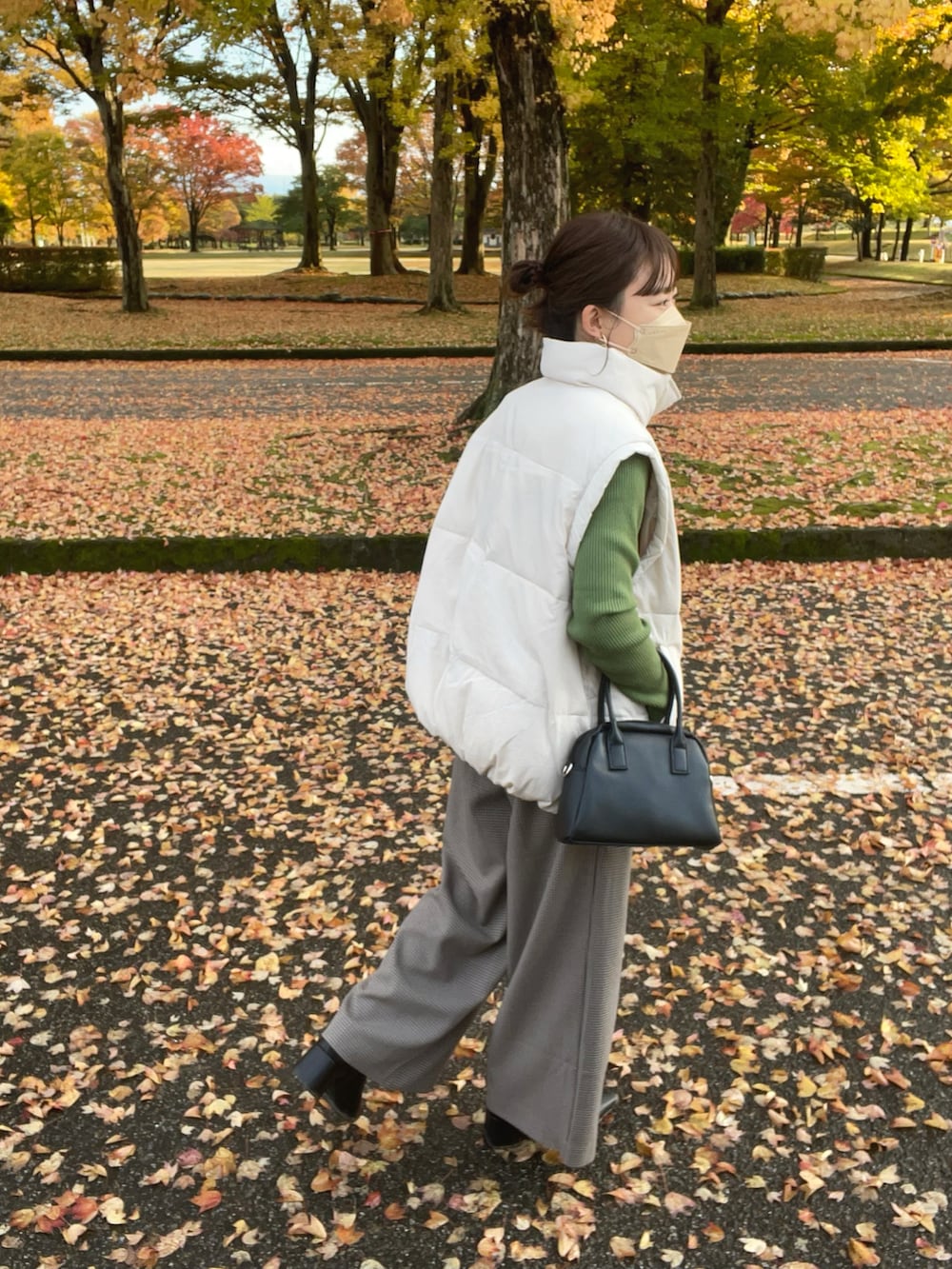 ベージュ系のその他パンツ、ホワイト系のダウンベスト、グリーン系のニット/セーターを着用したレディースの秋コーディネートの2枚目の写真