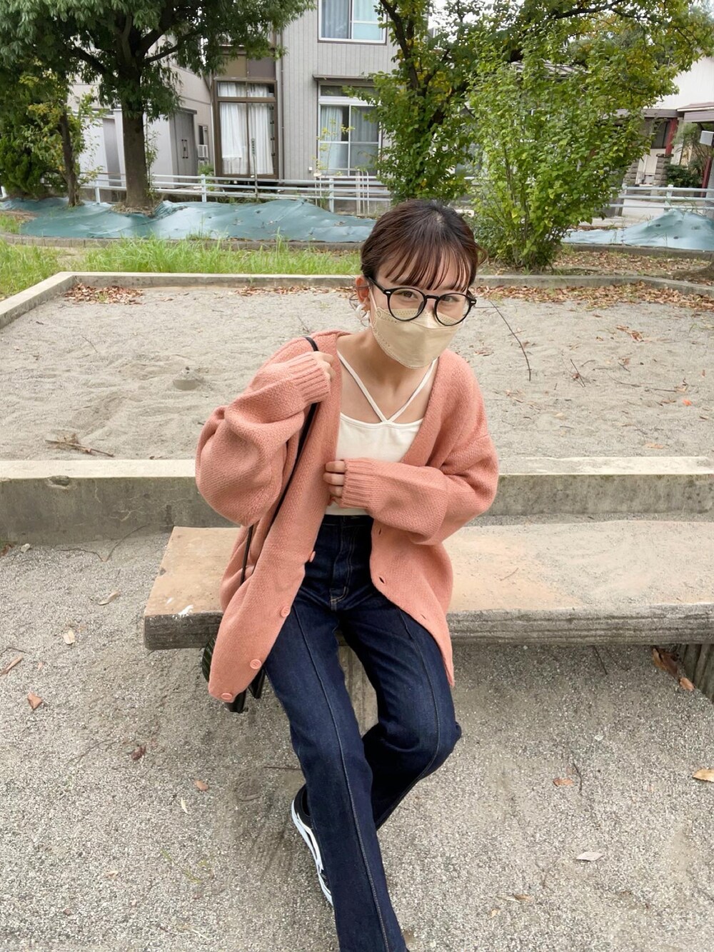 ピンク系のカーディガン/ボレロ、ホワイト系のキャミソール、ブラック系のデニムパンツを着用したレディースの秋コーディネートの5枚目の写真