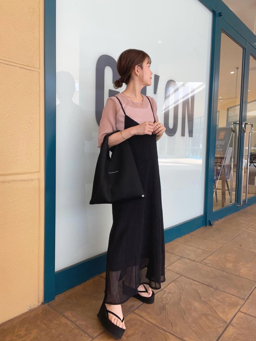ピンク系のシャツ/ブラウス、ブラック系のワンピース、ブラック系のトートバッグを着用したレディースの夏コーディネートの2枚目の写真