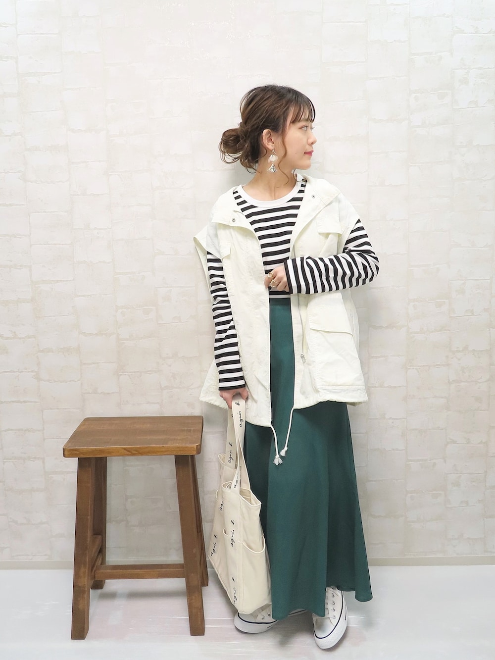 ブラック系のTシャツ/カットソー、ホワイト系のベスト、グリーン系のスカートを着用したレディースの春コーディネートの3枚目の写真