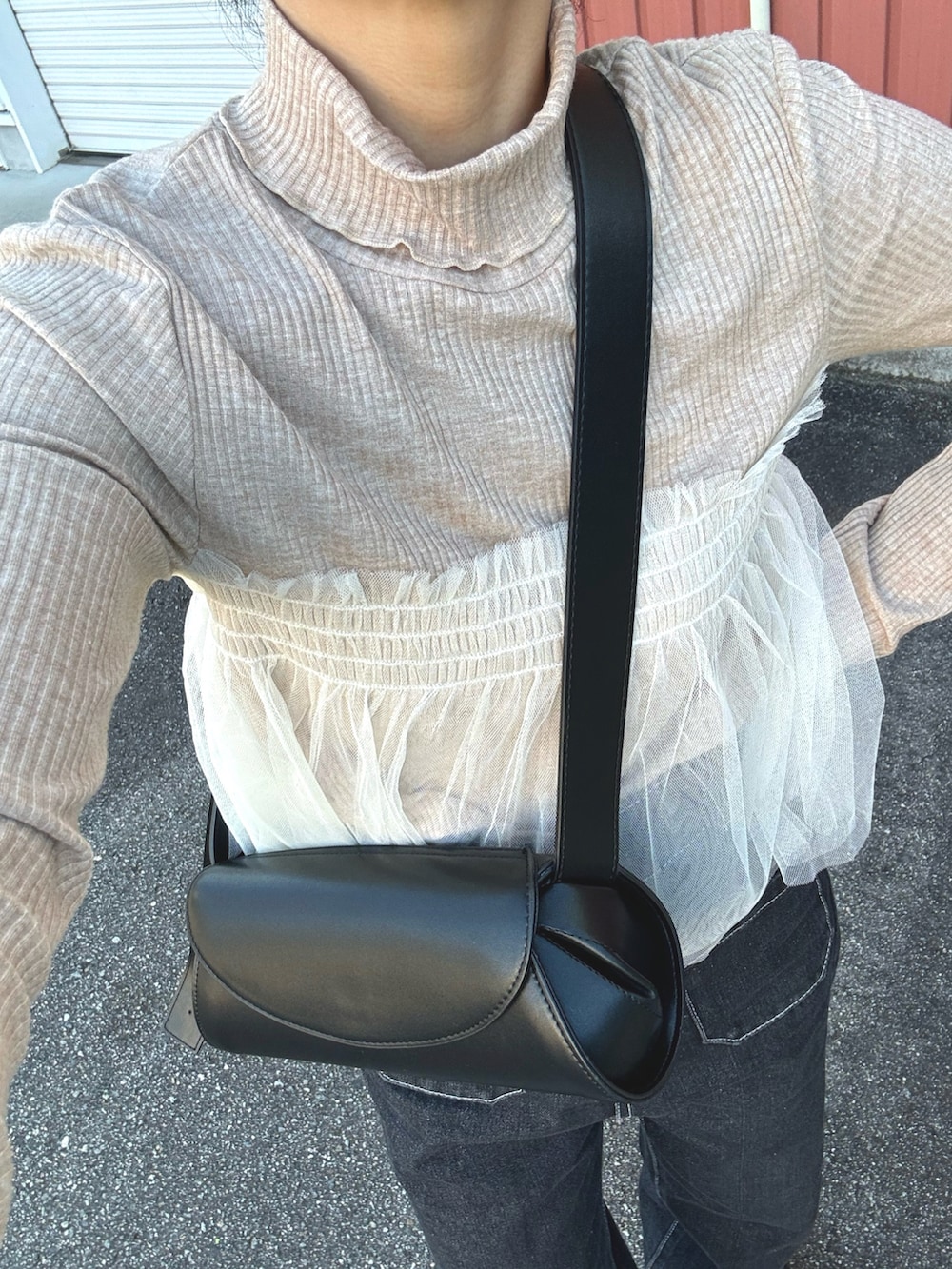 ベージュ系のTシャツ/カットソー、ブラック系のデニムパンツ、ブラック系のショルダーバッグを着用したレディースの秋コーディネートの3枚目の写真