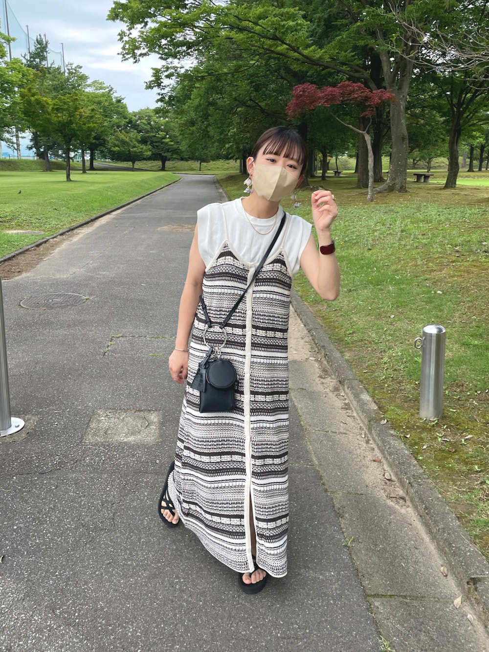 ベージュ系のワンピース、ホワイト系のニット/セーター、ブラック系のショルダーバッグを着用したレディースの夏コーディネートの2枚目の写真