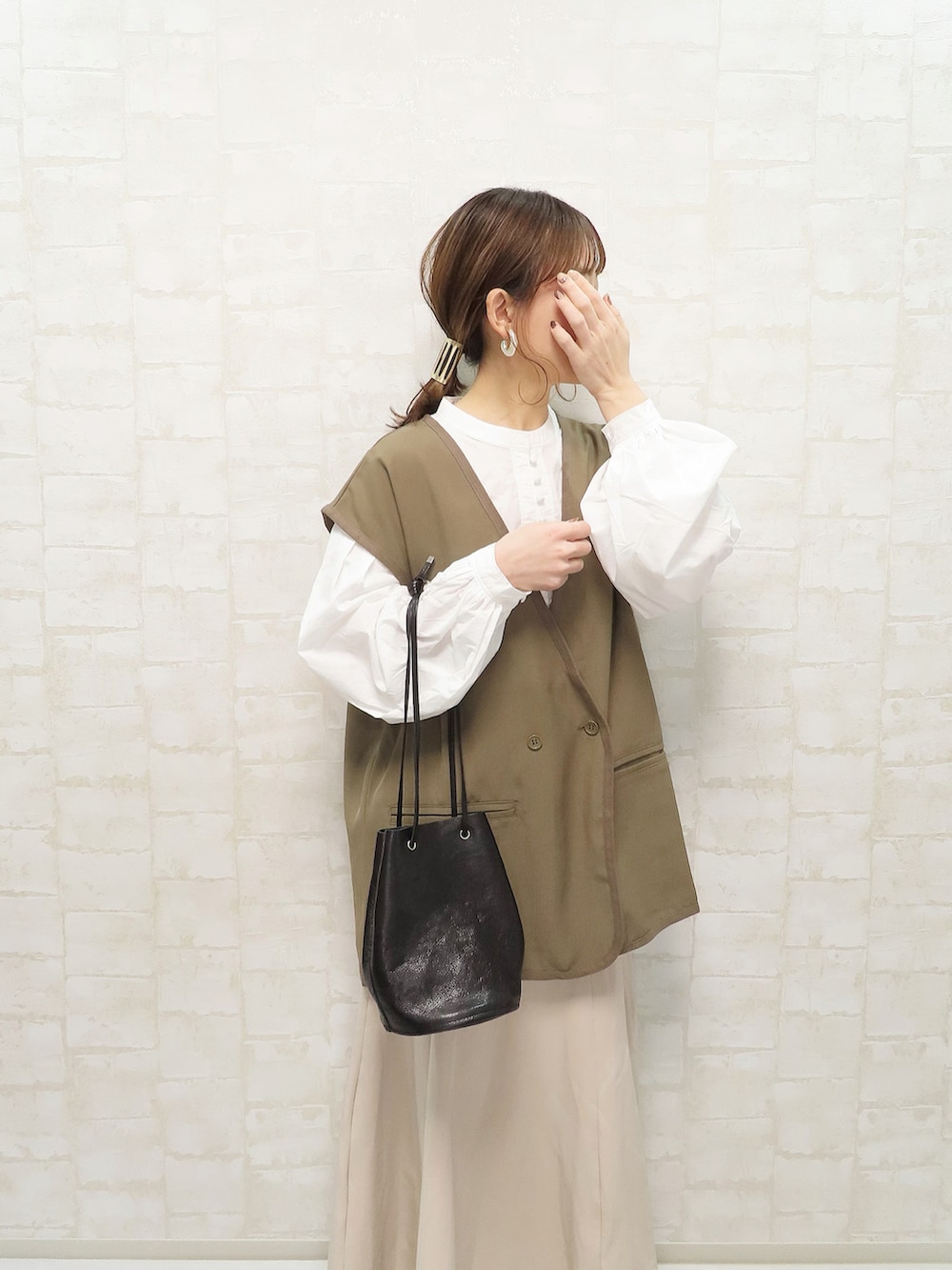 ホワイト系のシャツ/ブラウス、ブラウン系のベスト、ベージュ系のスカートを着用したレディースの冬コーディネートの3枚目の写真