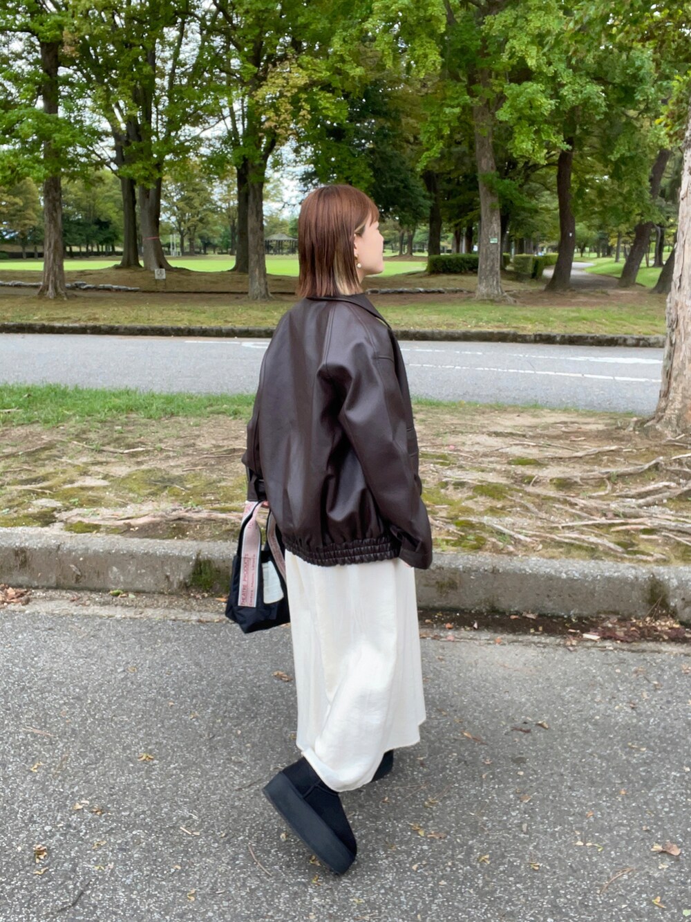 ブラック系のジャケット/アウター、ホワイト系のワンピース、ブラック系のブーツを着用したレディースの秋コーディネートの3枚目の写真