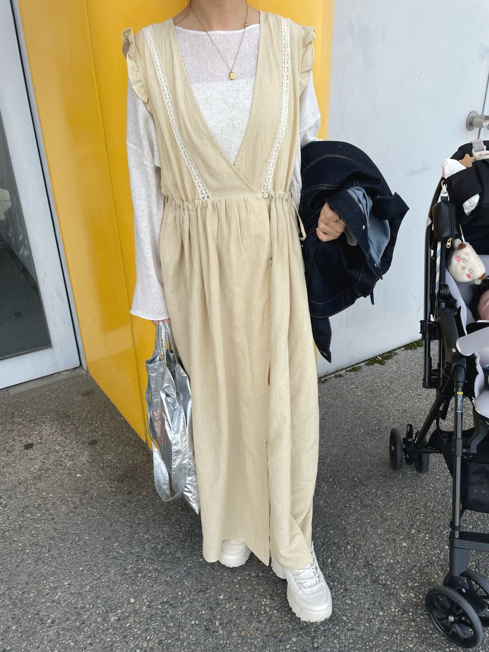 イエロー系のワンピース、ブルー系のデニムジャケット、シルバー系のトートバッグを着用したレディースの春コーディネートの5枚目の写真