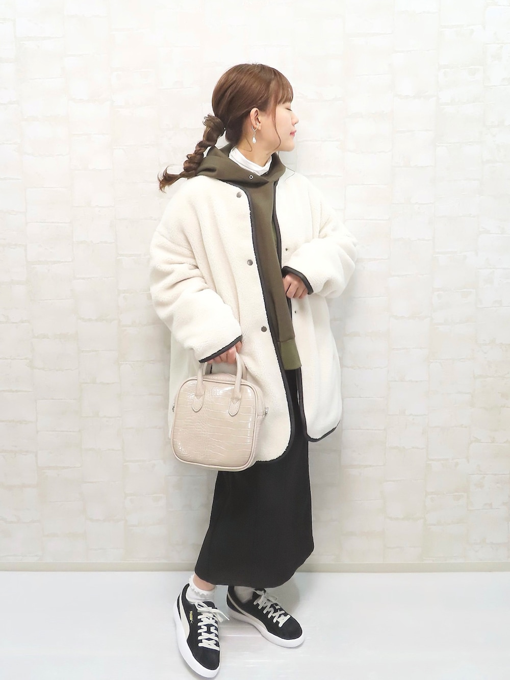 グリーン系のパーカー、ホワイト系のその他アウター、ベージュ系のショルダーバッグを着用したレディースの冬コーディネートの2枚目の写真