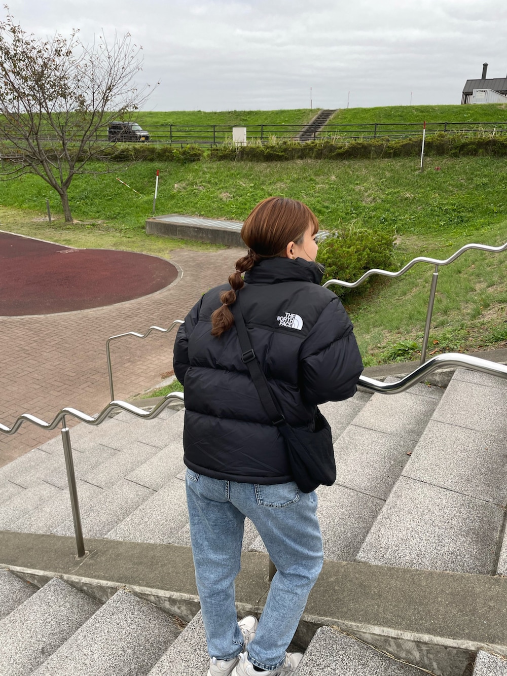 ブラック系のダウンジャケット/コート、ホワイト系のニット/セーター、ブルー系のデニムパンツを着用したレディースの冬コーディネートの5枚目の写真