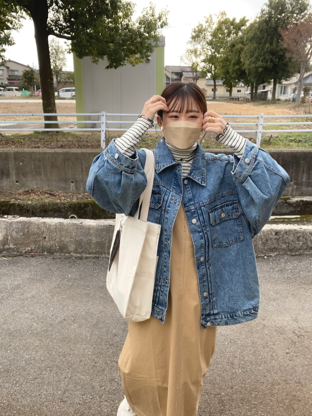 ベージュ系のワンピース、ホワイト系のトートバッグ、ブルー系のデニムジャケットを着用したレディースの春コーディネートの4枚目の写真