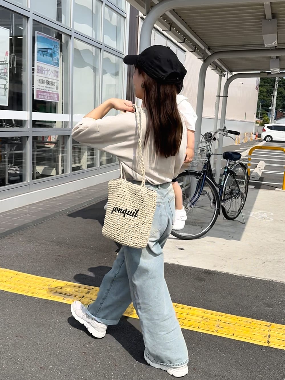 ベージュ系のトップス、ブルー系のデニムパンツ、ベージュ系のかごバッグを着用したレディースの夏コーディネートの3枚目の写真