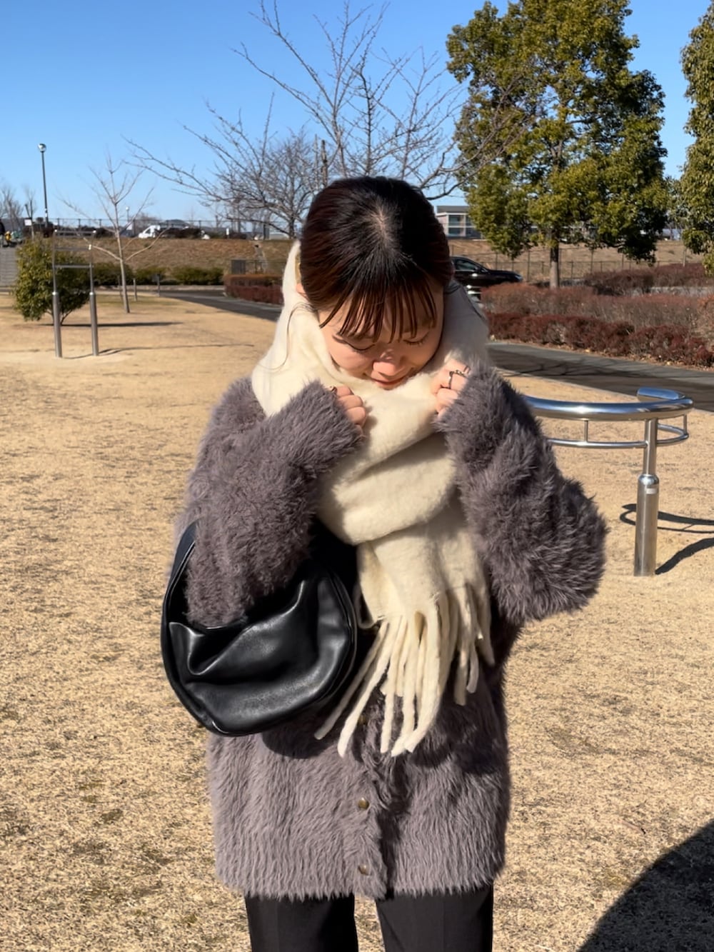 ベージュ系のカーディガン/ボレロ、ブラック系のスラックス、ホワイト系のスニーカーを着用したレディースの冬コーディネートの2枚目の写真