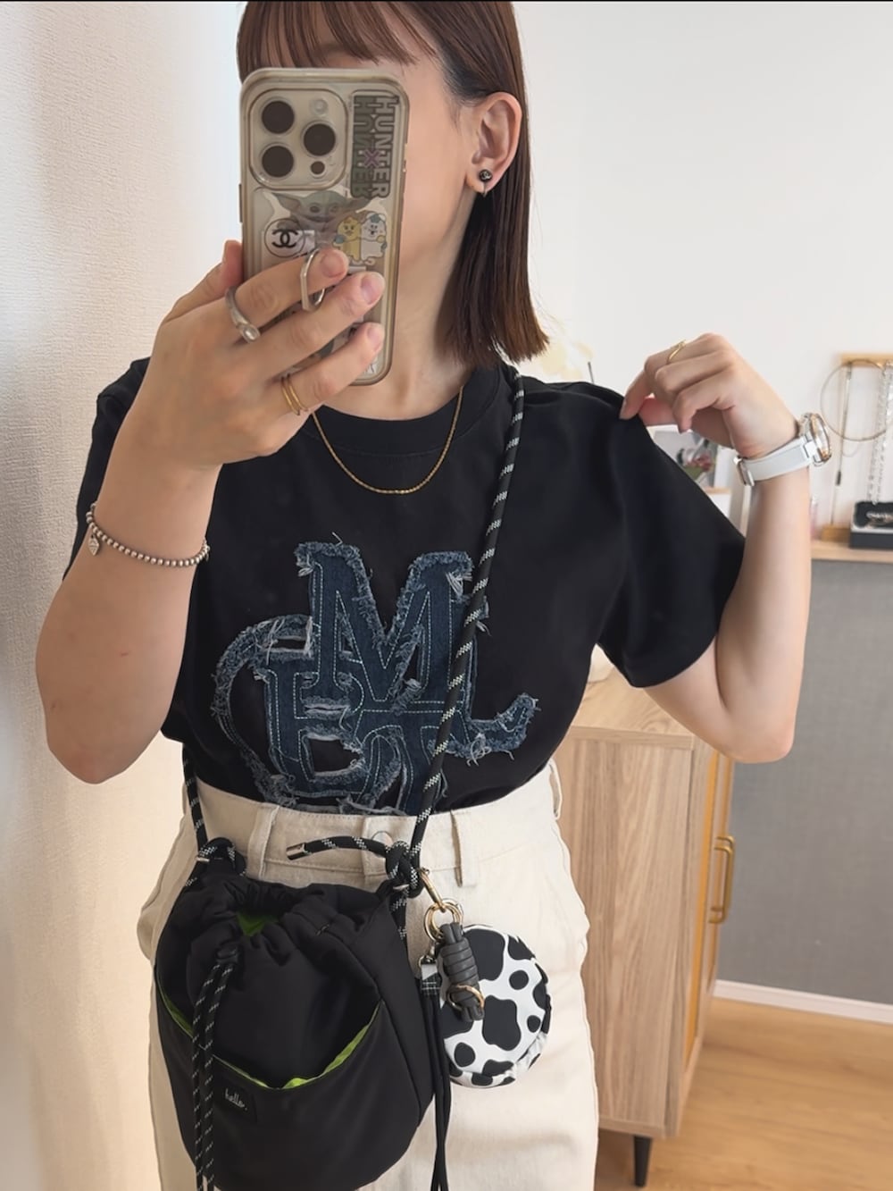 ブラック系のTシャツ/カットソー、ホワイト系のデニムスカート、ブラック系のバッグを着用したレディースの夏コーディネートの3枚目の写真