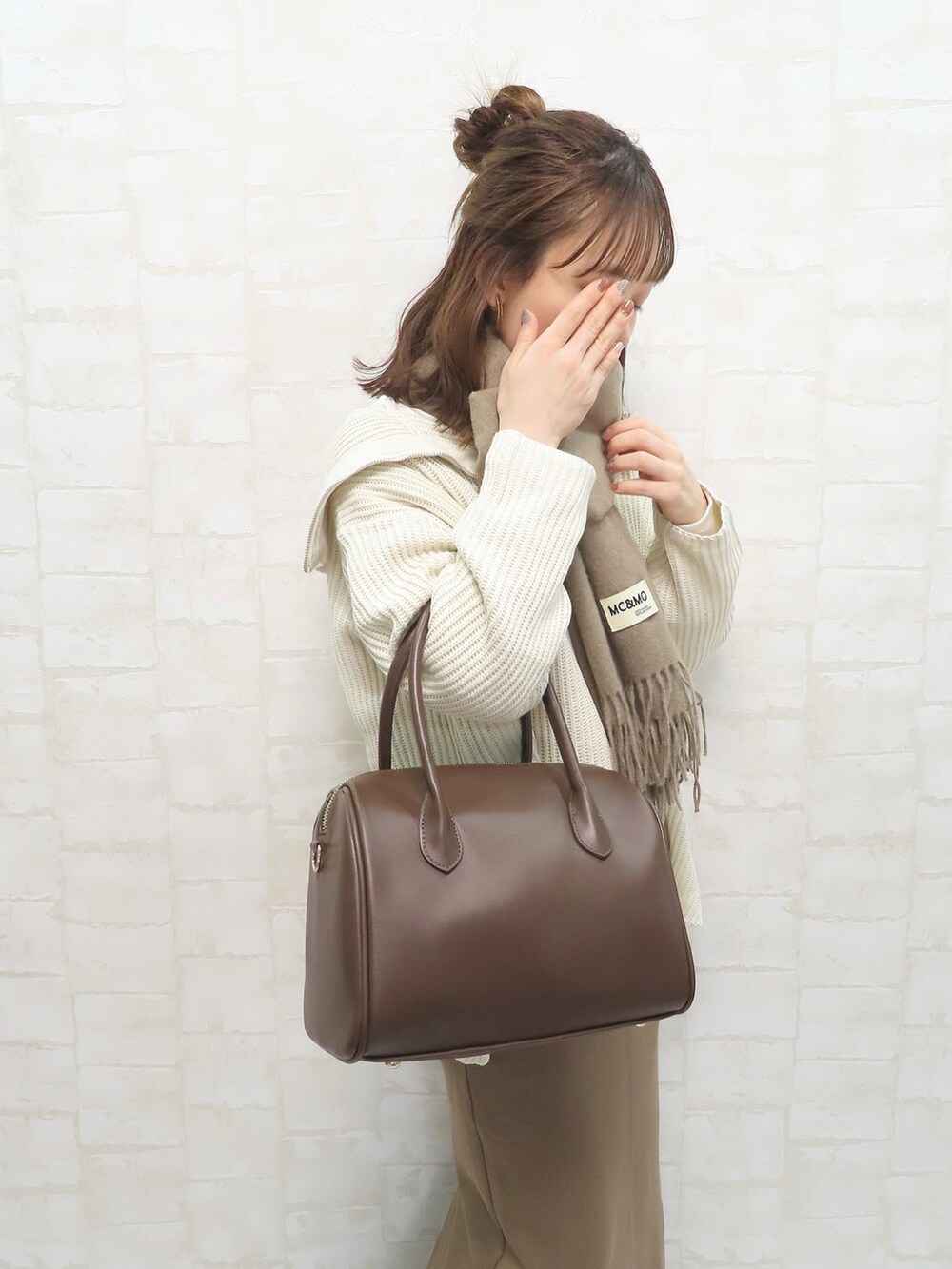 ホワイト系のニット/セーター、ブラウン系のボストンバッグ、ブラウン系のスカートを着用したレディースの冬コーディネートの2枚目の写真