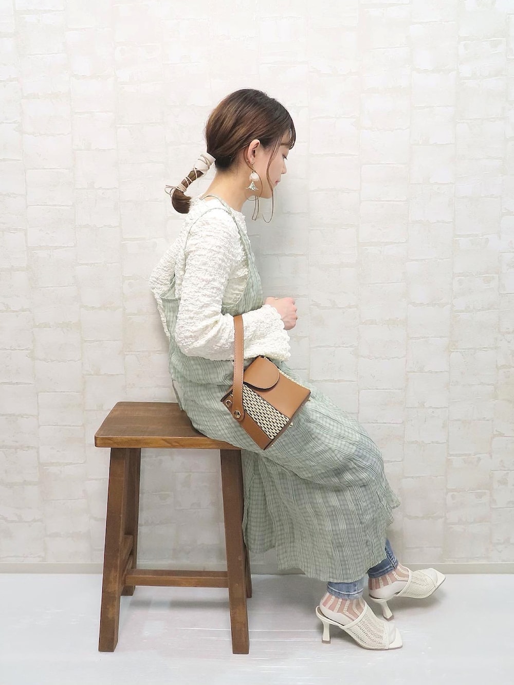 グリーン系のワンピース、ホワイト系のTシャツ/カットソー、ブルー系のデニムパンツを着用したレディースの春コーディネートの2枚目の写真