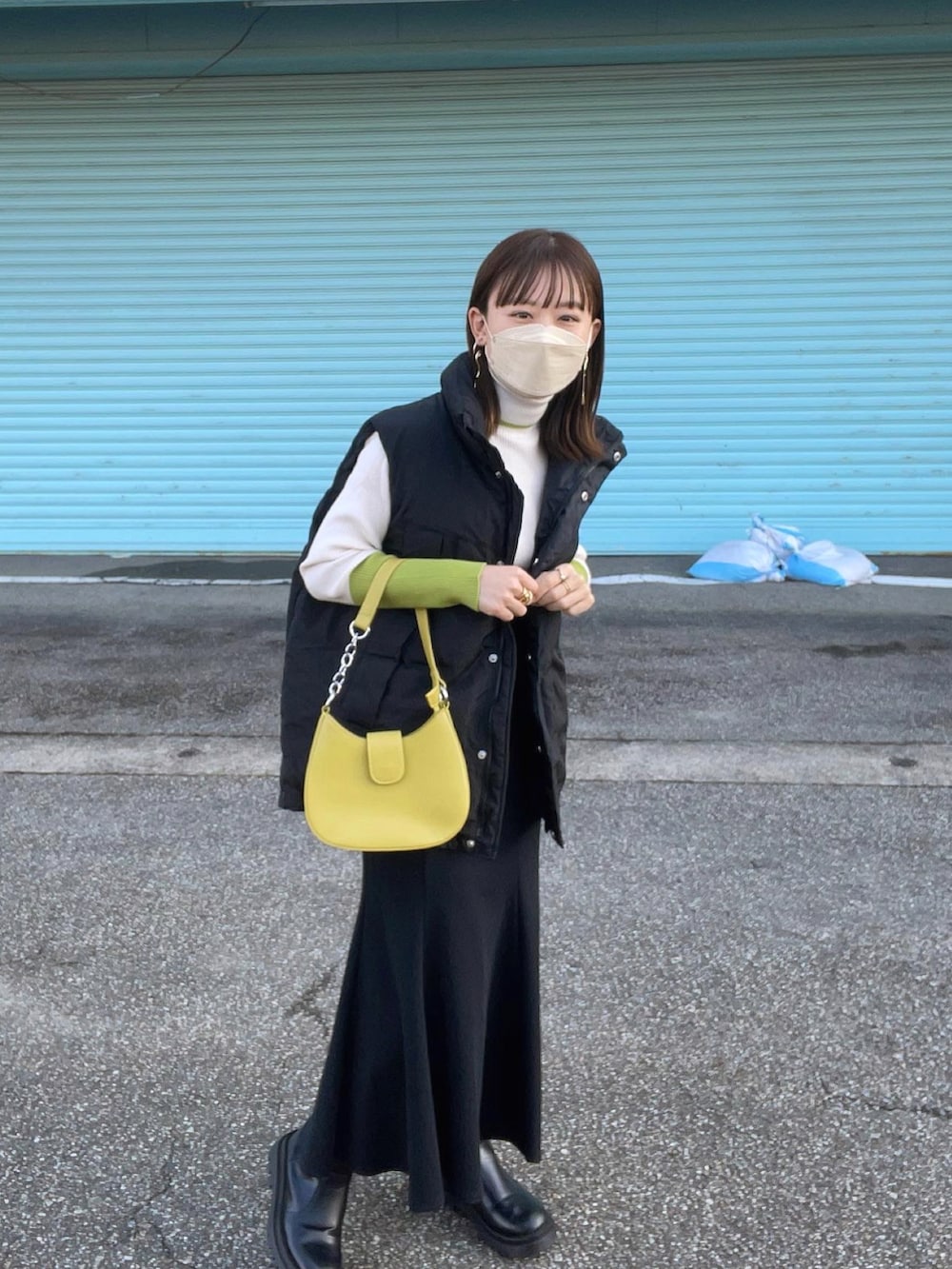 ホワイト系のニット/セーター、ブラック系のダウンベスト、ブラック系のスカートを着用したレディースの秋コーディネートの5枚目の写真