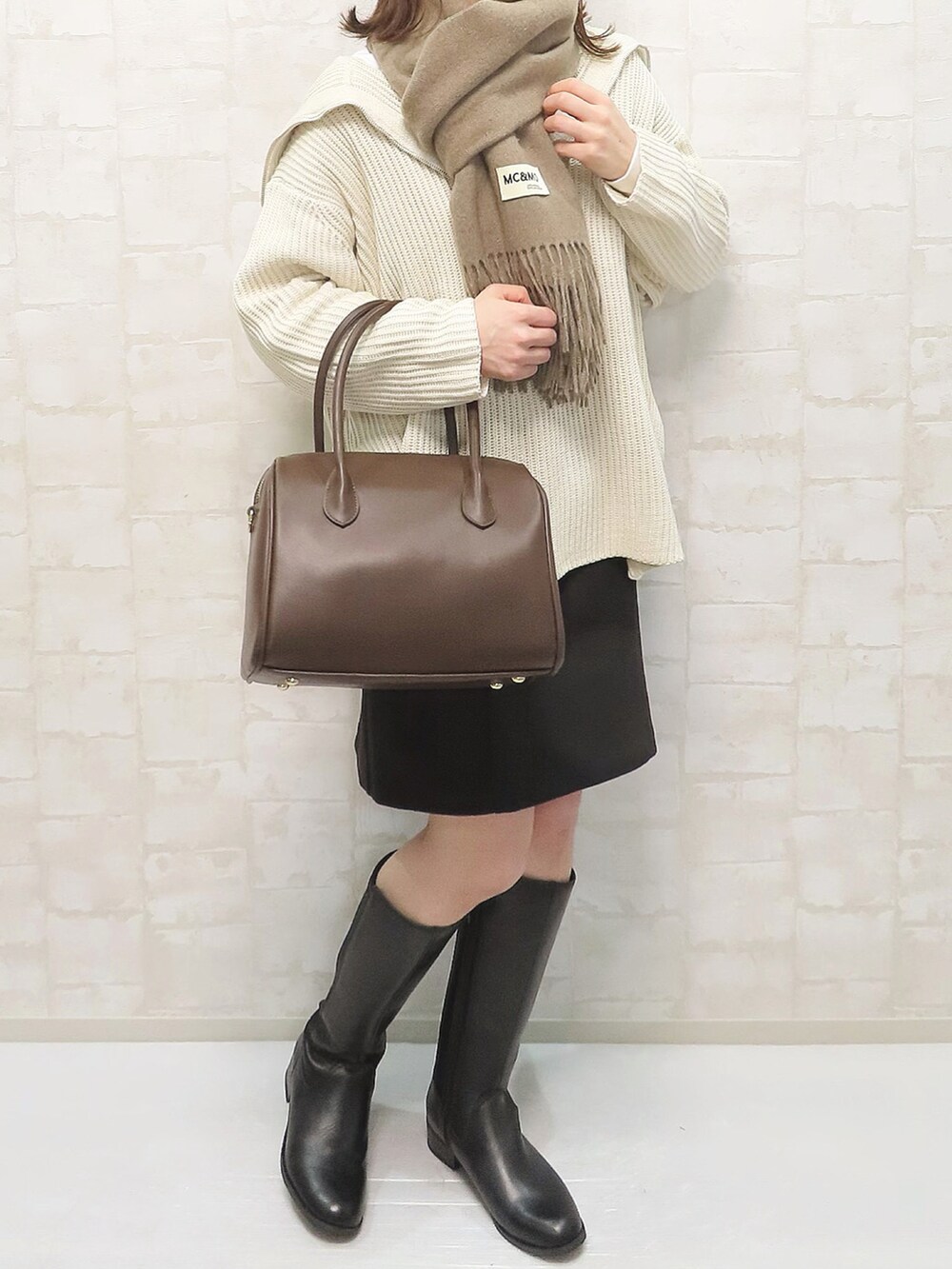 ホワイト系のニット/セーター、ブラック系のスカート、ブラック系のブーツを着用したレディースの冬コーディネートの2枚目の写真