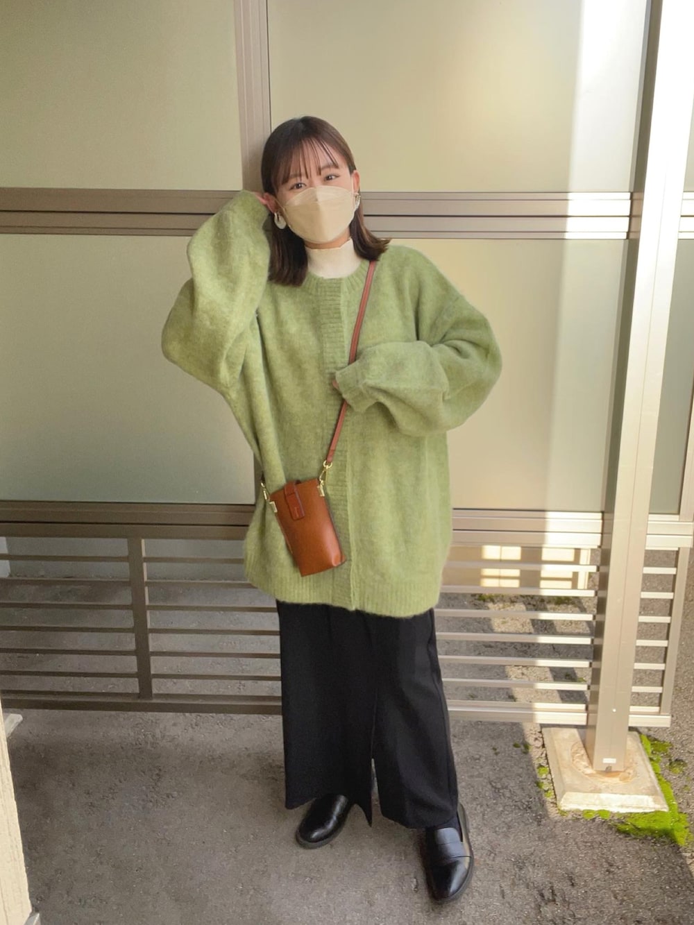 グリーン系のカーディガン/ボレロ、ホワイト系のニット/セーター、ブラック系のスカートを着用したレディースの冬コーディネートの2枚目の写真