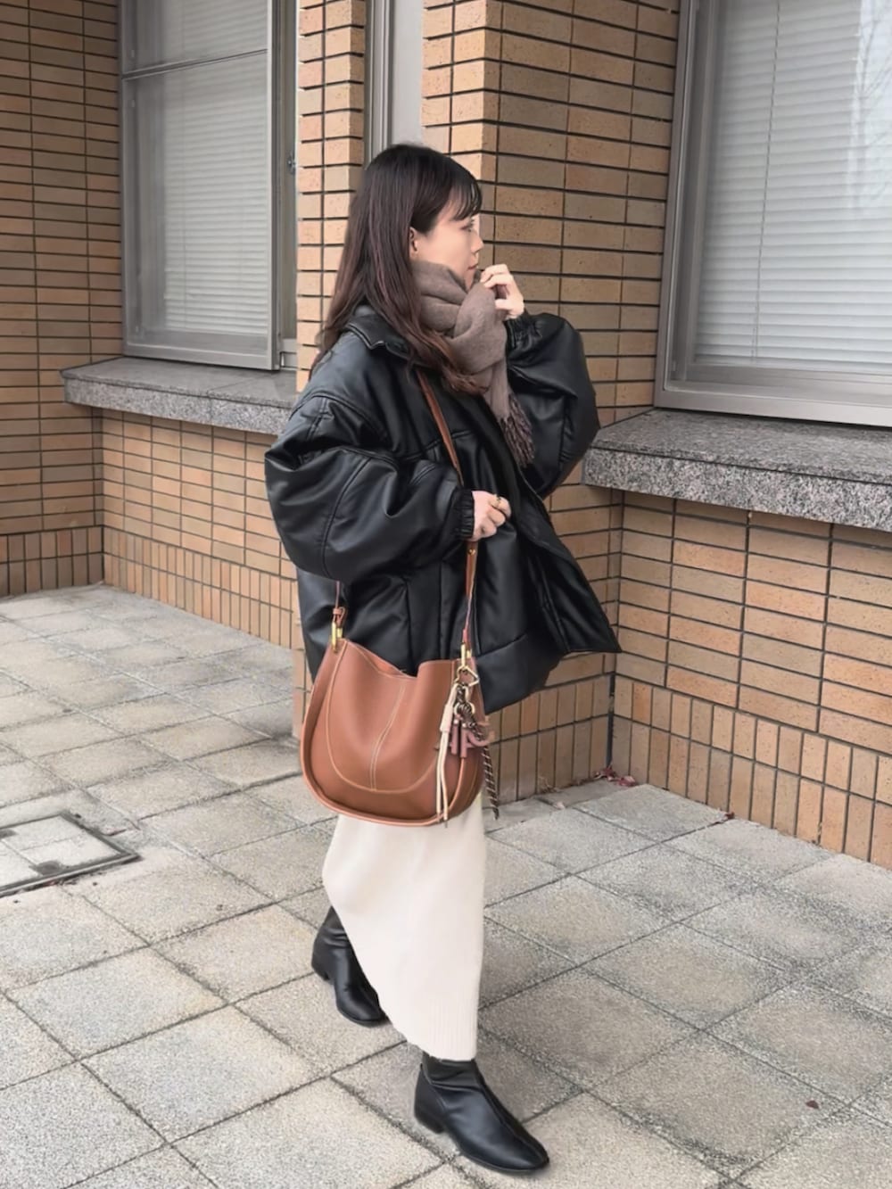 ブラック系のブルゾン、ホワイト系のワンピース、ブラウン系のショルダーバッグを着用したレディースの冬コーディネートの2枚目の写真
