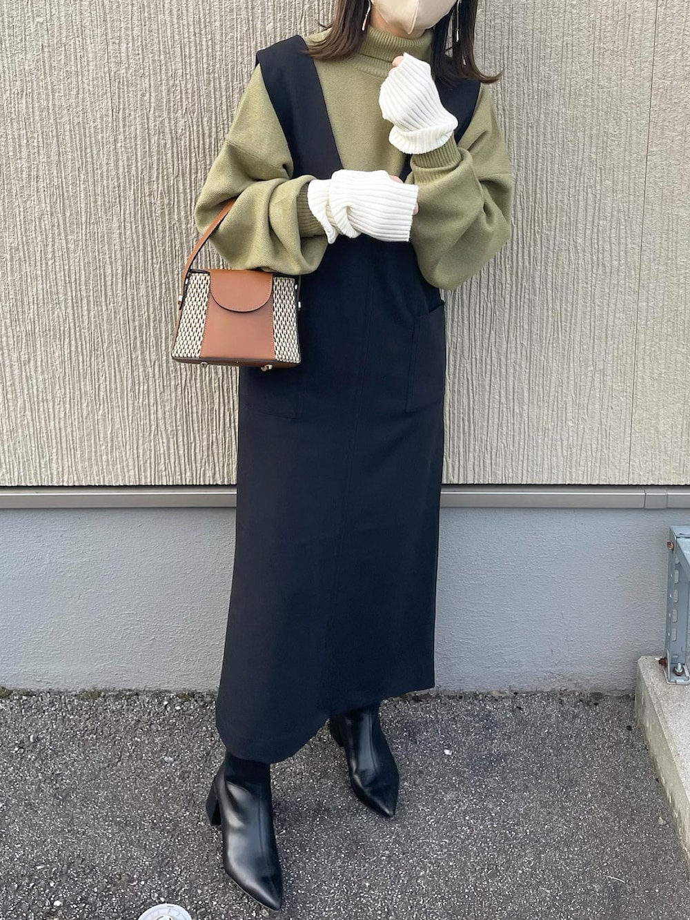 ブラック系のジャンパースカート、グリーン系のニット/セーター、イエロー系のショルダーバッグを着用したレディースの秋コーディネートの5枚目の写真