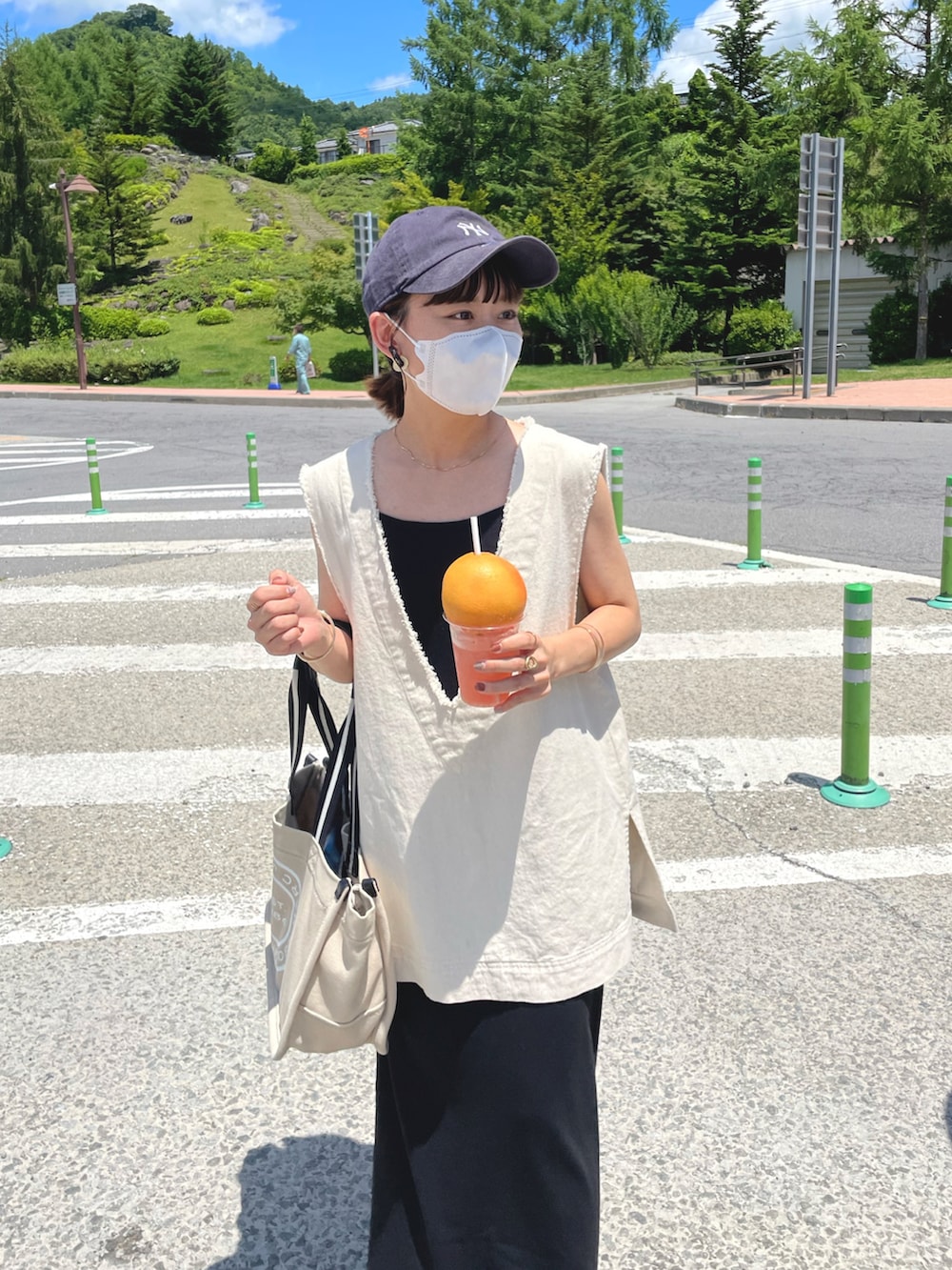 ホワイト系のベスト、ブラック系のワンピース、ベージュ系のトートバッグを着用したレディースの夏コーディネートの2枚目の写真