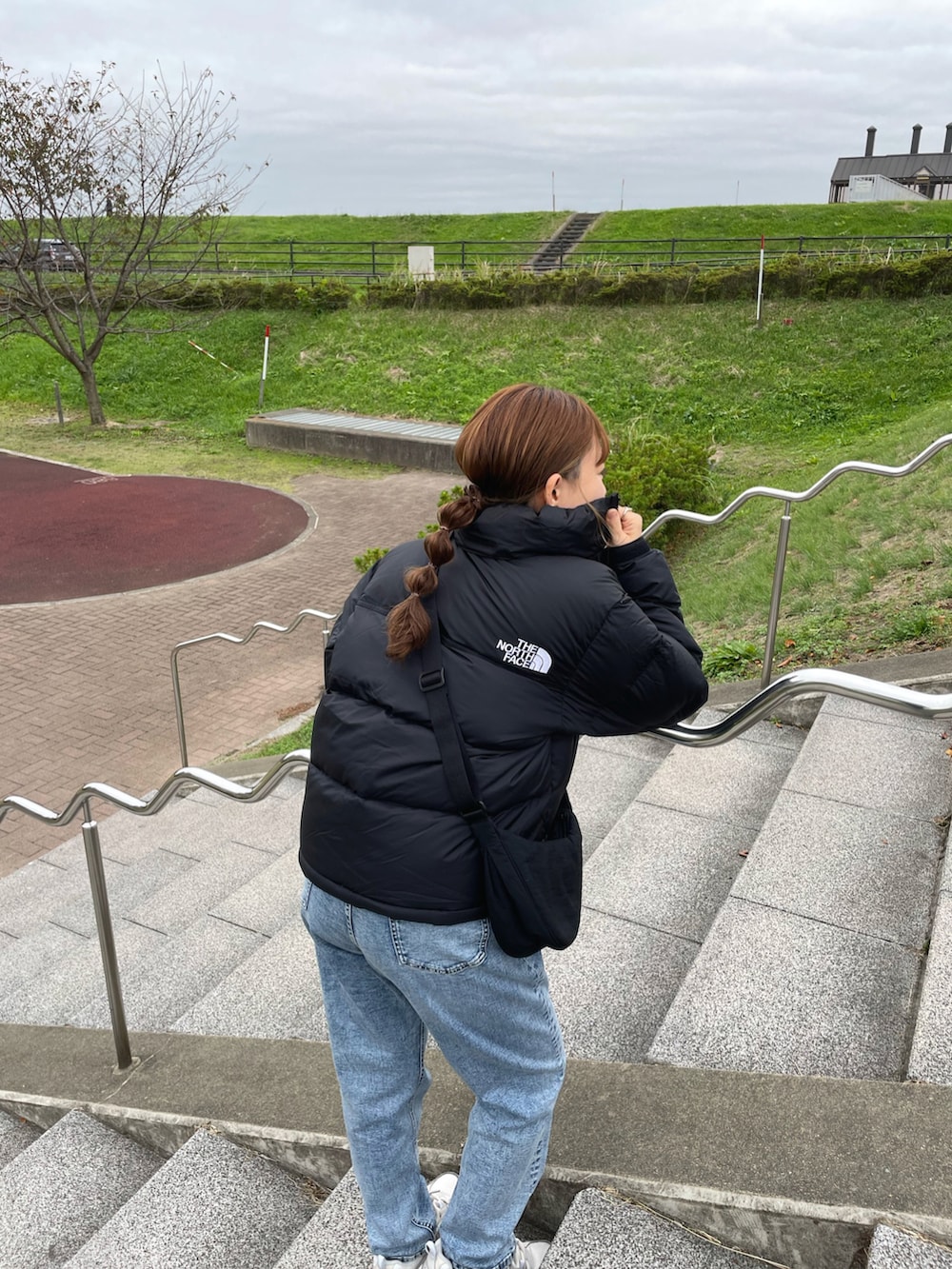 ブラック系のダウンジャケット/コート、ホワイト系のニット/セーター、ブルー系のデニムパンツを着用したレディースの冬コーディネートの2枚目の写真