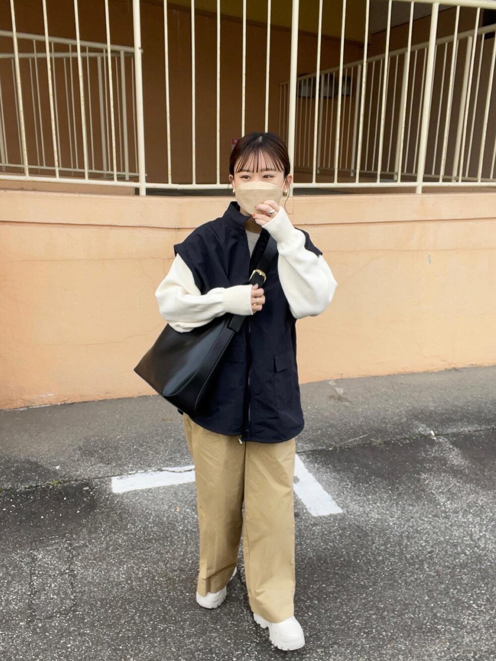 ベージュ系のその他パンツ、ホワイト系のニット/セーター、ブラック系のマウンテンパーカーを着用したレディースの春コーディネートの3枚目の写真