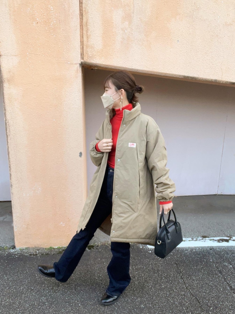 ベージュ系のダウンジャケット/コート、レッド系のトップス、ブルー系のデニムパンツを着用したレディースの冬コーディネートの3枚目の写真