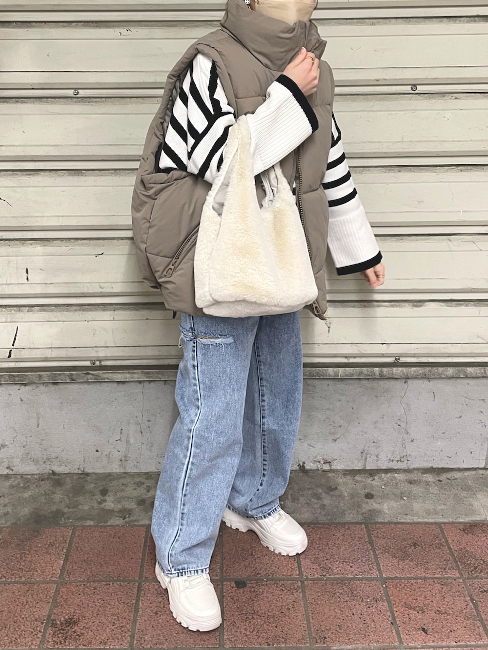 ホワイト系のニット/セーター、その他のデニムパンツ、ベージュ系のダウンベストを着用したレディースの冬コーディネートの3枚目の写真