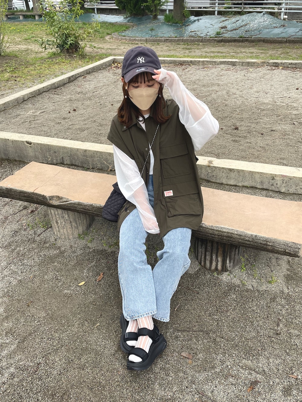 グリーン系のマウンテンパーカー、ホワイト系のTシャツ/カットソー、ブルー系のデニムパンツを着用したレディースの春コーディネートの2枚目の写真