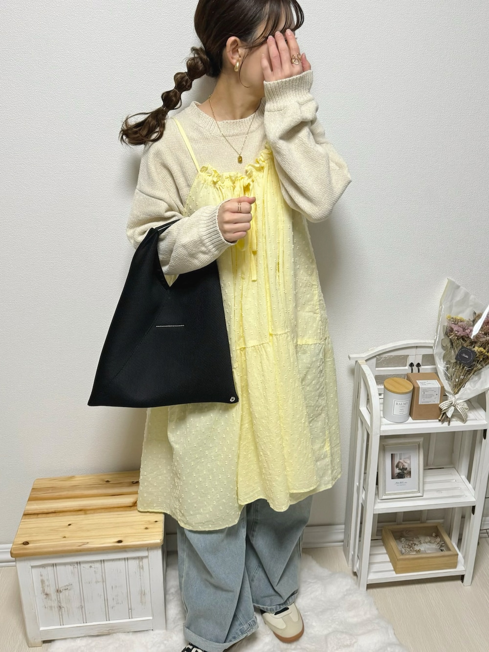 イエロー系のワンピース、ブルー系のデニムパンツ、ベージュ系のスニーカーを着用したレディースの冬コーディネートの4枚目の写真