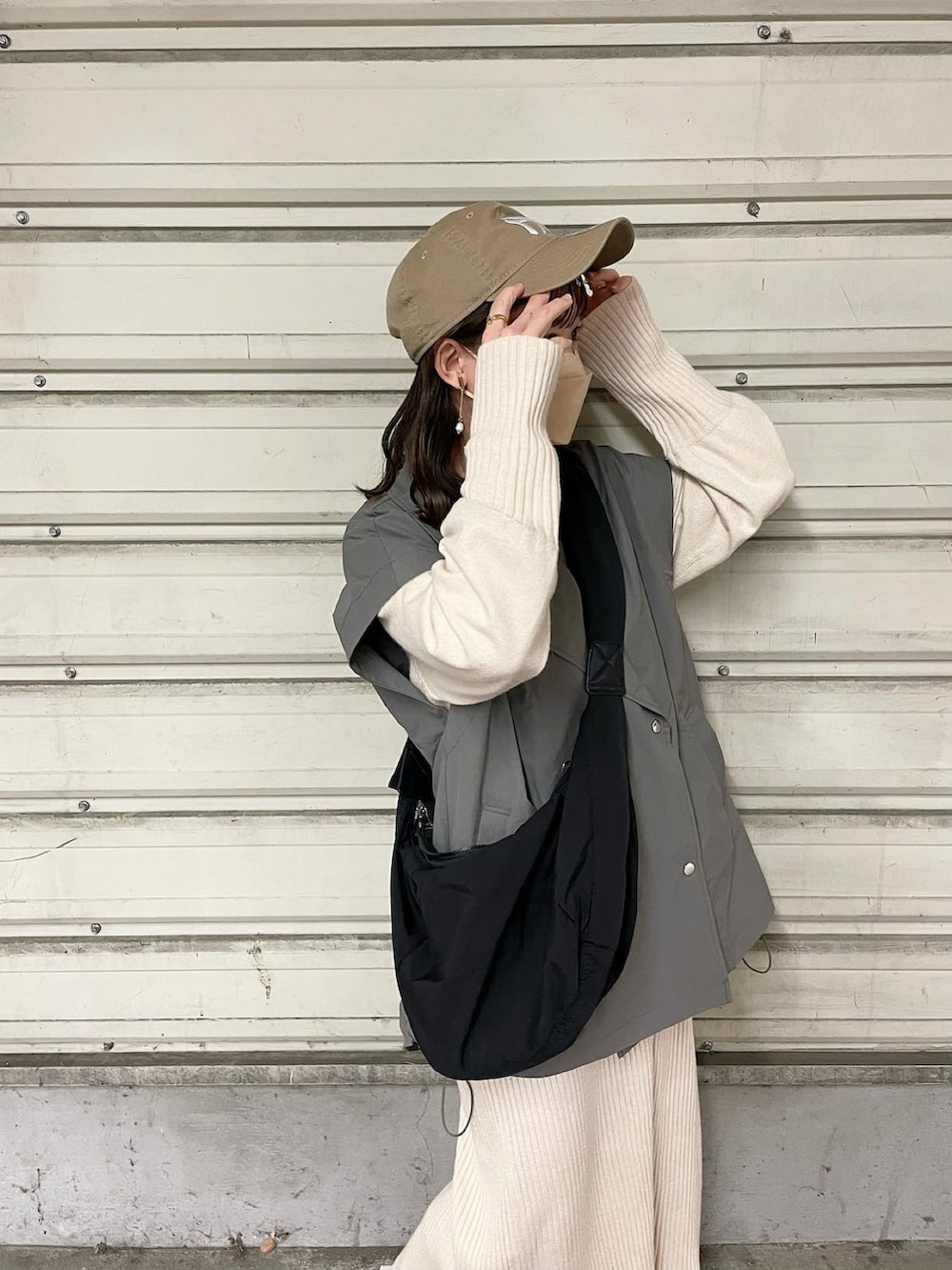 グレー系のミリタリージャケット、ホワイト系のワンピース、ブラック系のショルダーバッグを着用したレディースの春コーディネートの3枚目の写真