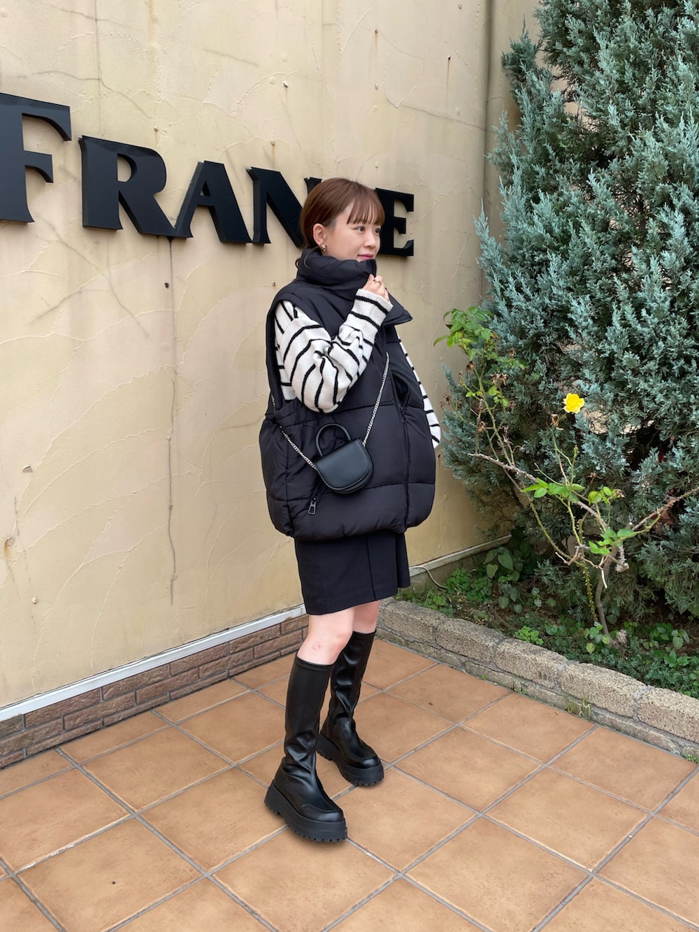 ブラック系のベスト、ブラック系のショルダーバッグ、ホワイト系のニット/セーターを着用したレディースの秋コーディネートの4枚目の写真