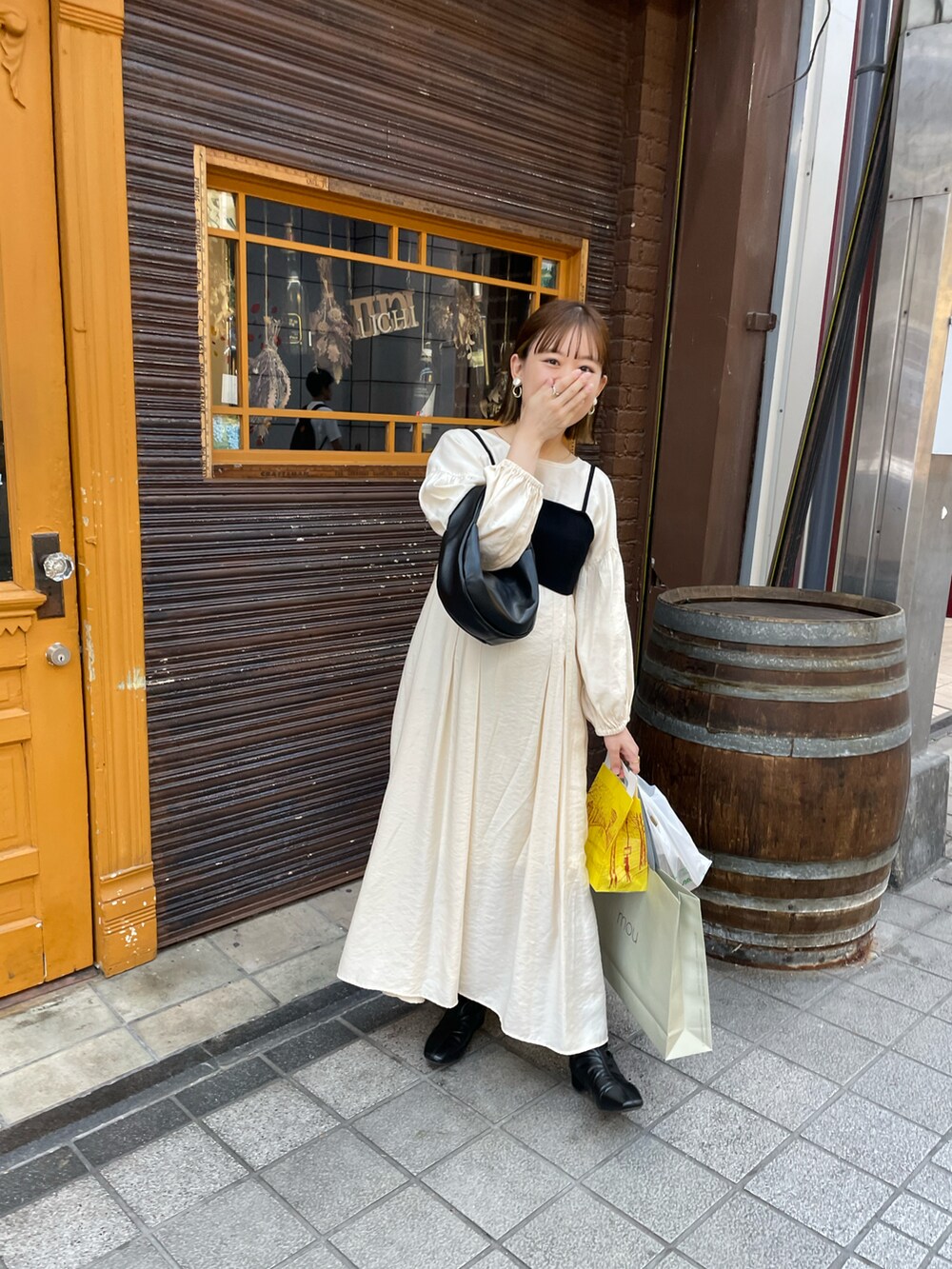 ホワイト系のワンピース、ブラック系のハンドバッグ、ブラック系のブーツを着用したレディースの秋コーディネートの4枚目の写真