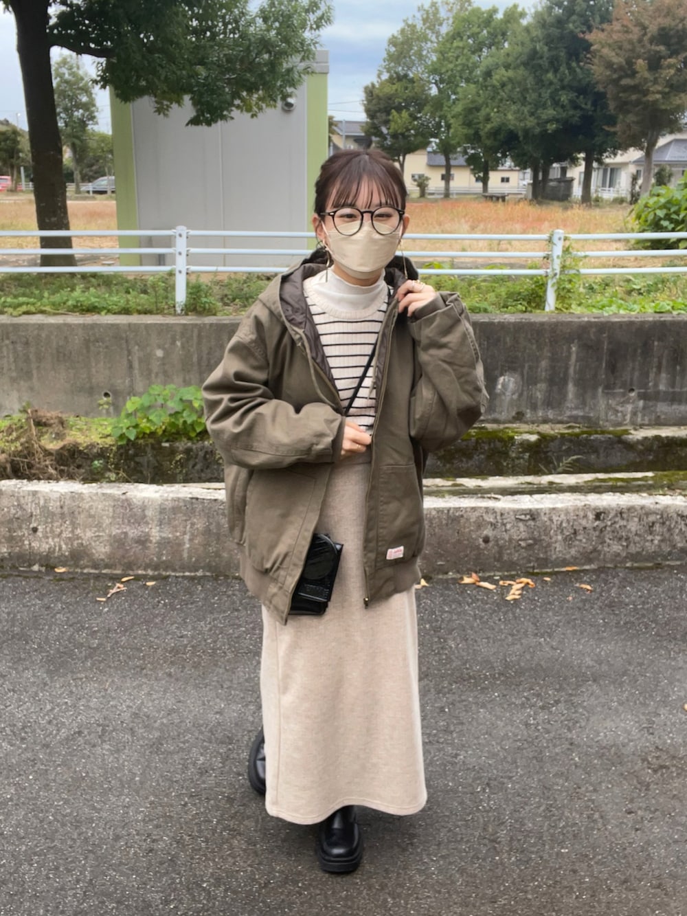 グリーン系のブルゾン、ホワイト系のニット/セーター、ホワイト系のTシャツ/カットソーを着用したレディースの冬コーディネートの2枚目の写真